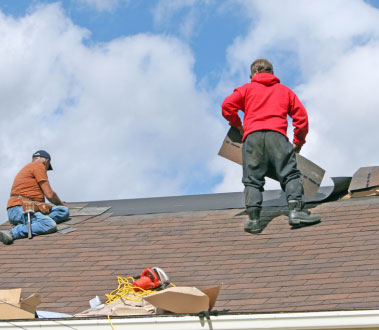 The image shows two men working on a roof repair, with shingles removed and the sky visible in the background.