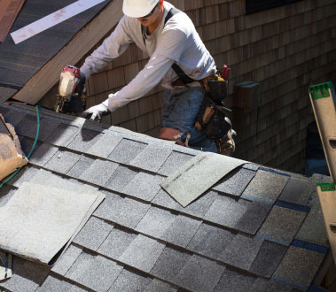 A construction worker installing shingles on a roof.