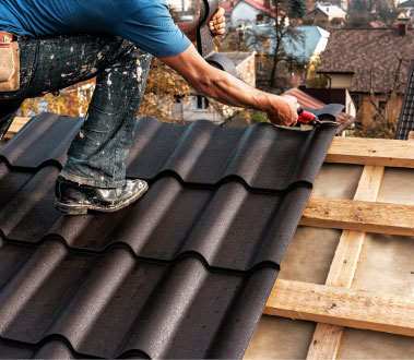 The image shows a construction worker on a roof, working with tools and materials, likely installing or repairing a metal roof.