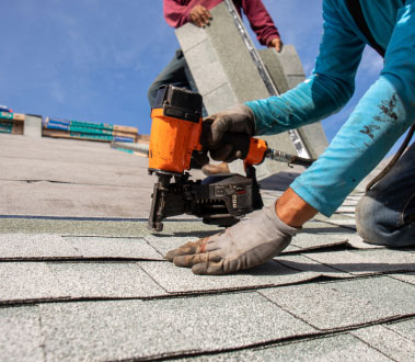 The image depicts two construction workers engaged in roofing work on a building.