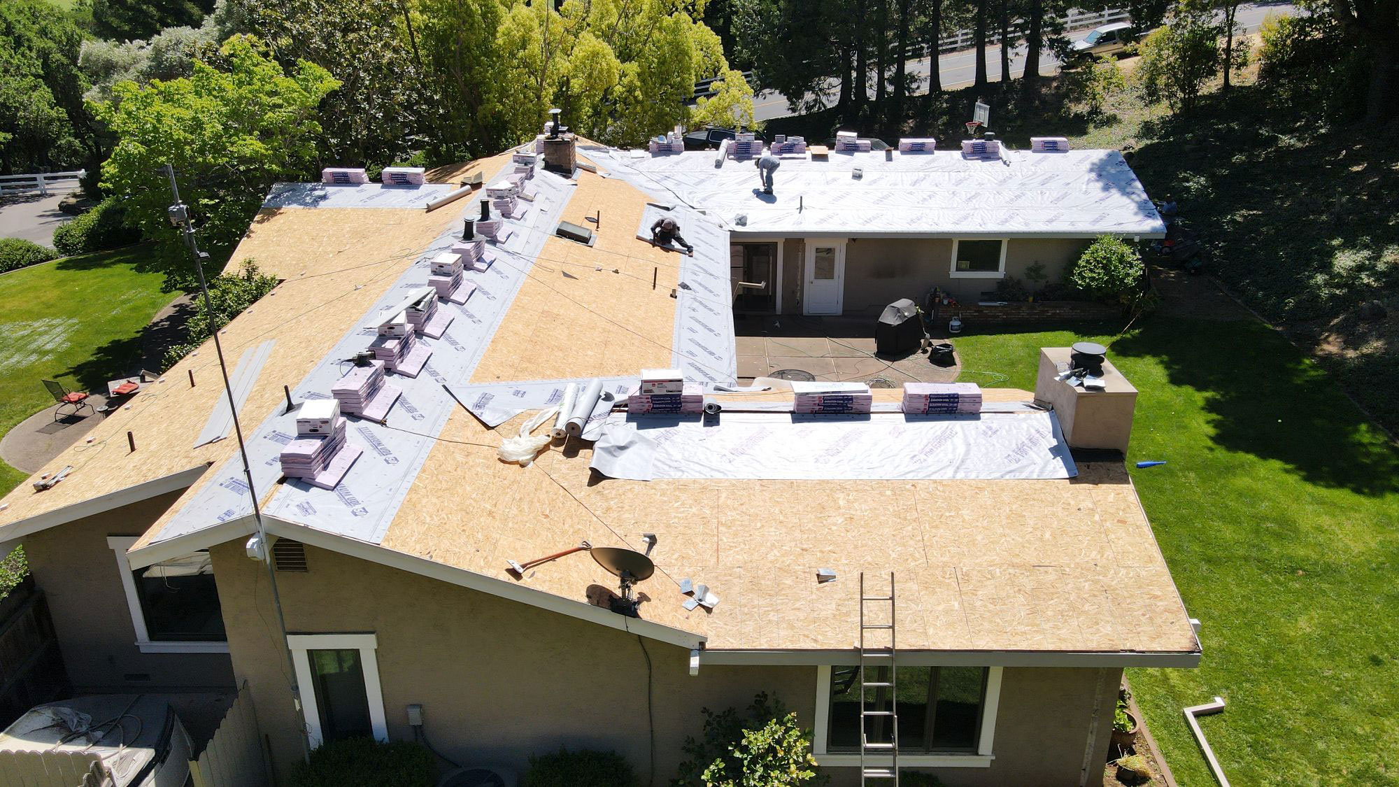 New roof construction with protective sheeting on a residential property.