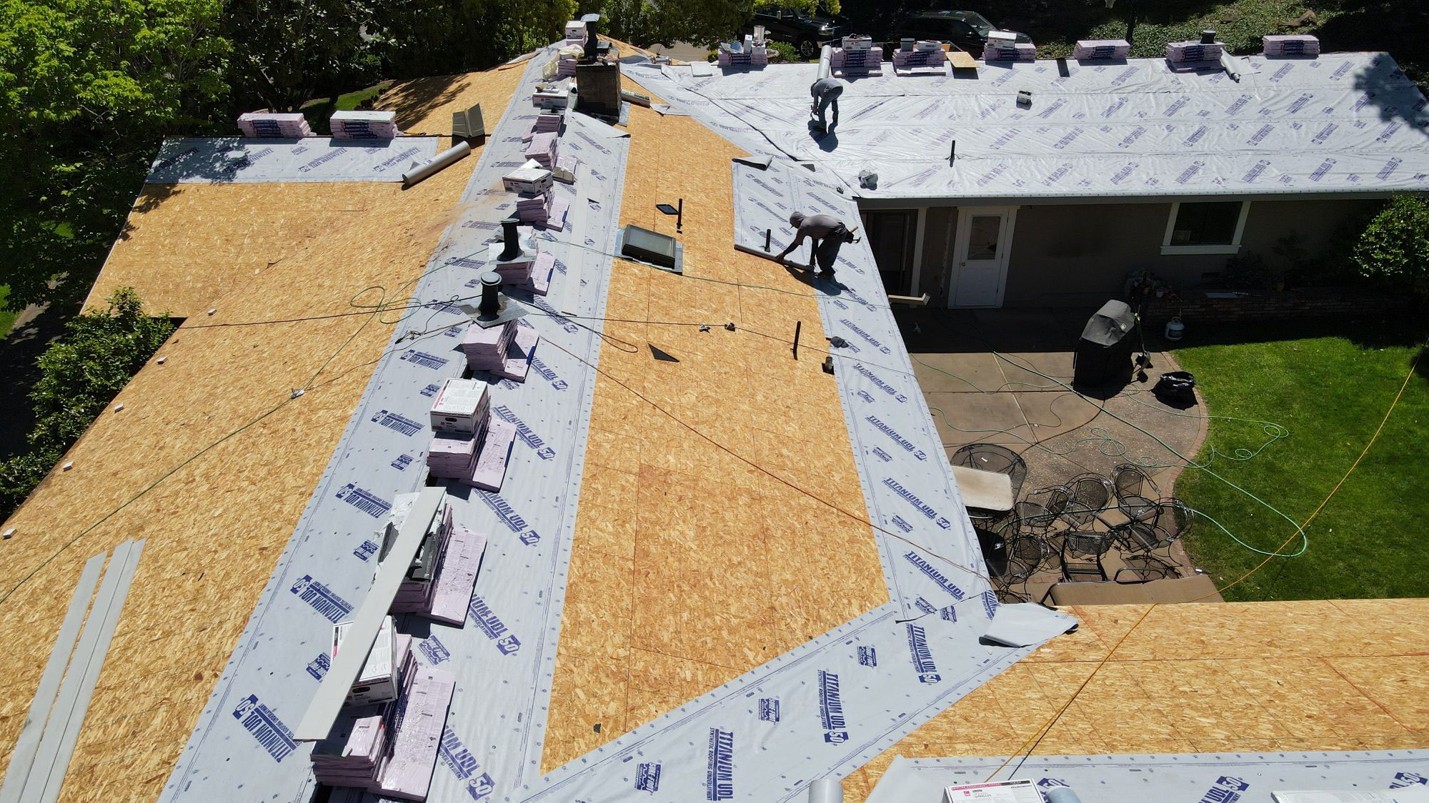 A house under construction with roofing materials installed, viewed from an angle above, showcasing the progress of the building project.