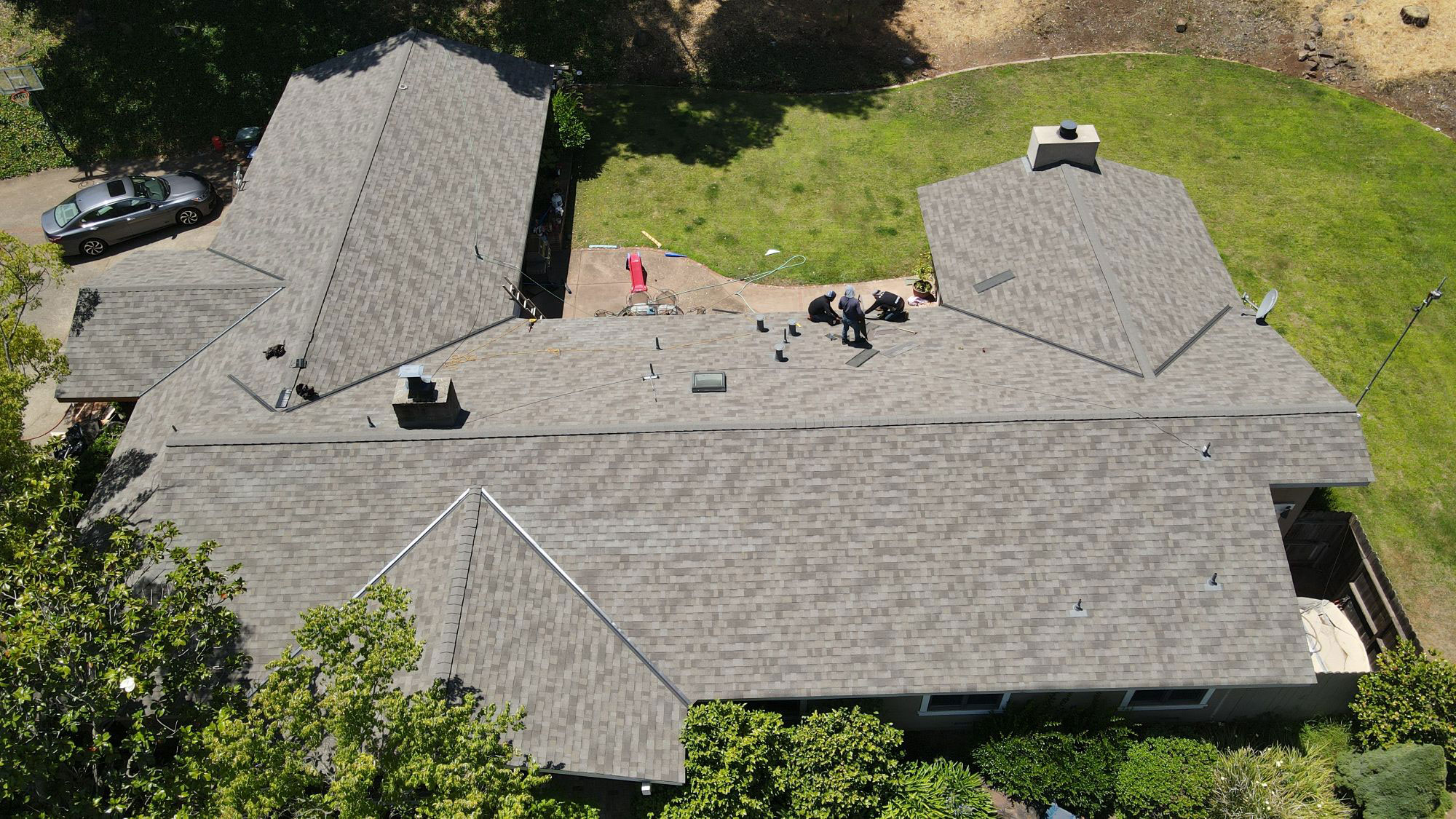 The image shows a two-story residential house with a shingled roof, a prominent front porch, and a yard visible in the background.