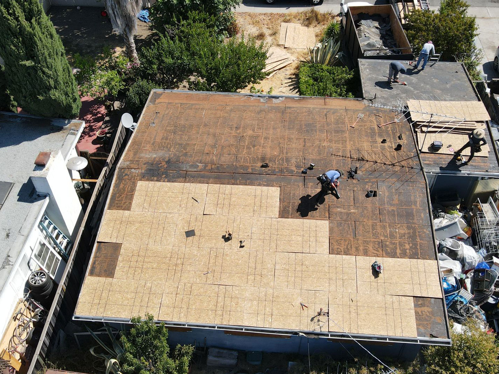 The image shows a construction site with a partially completed roof structure undergoing repairs.