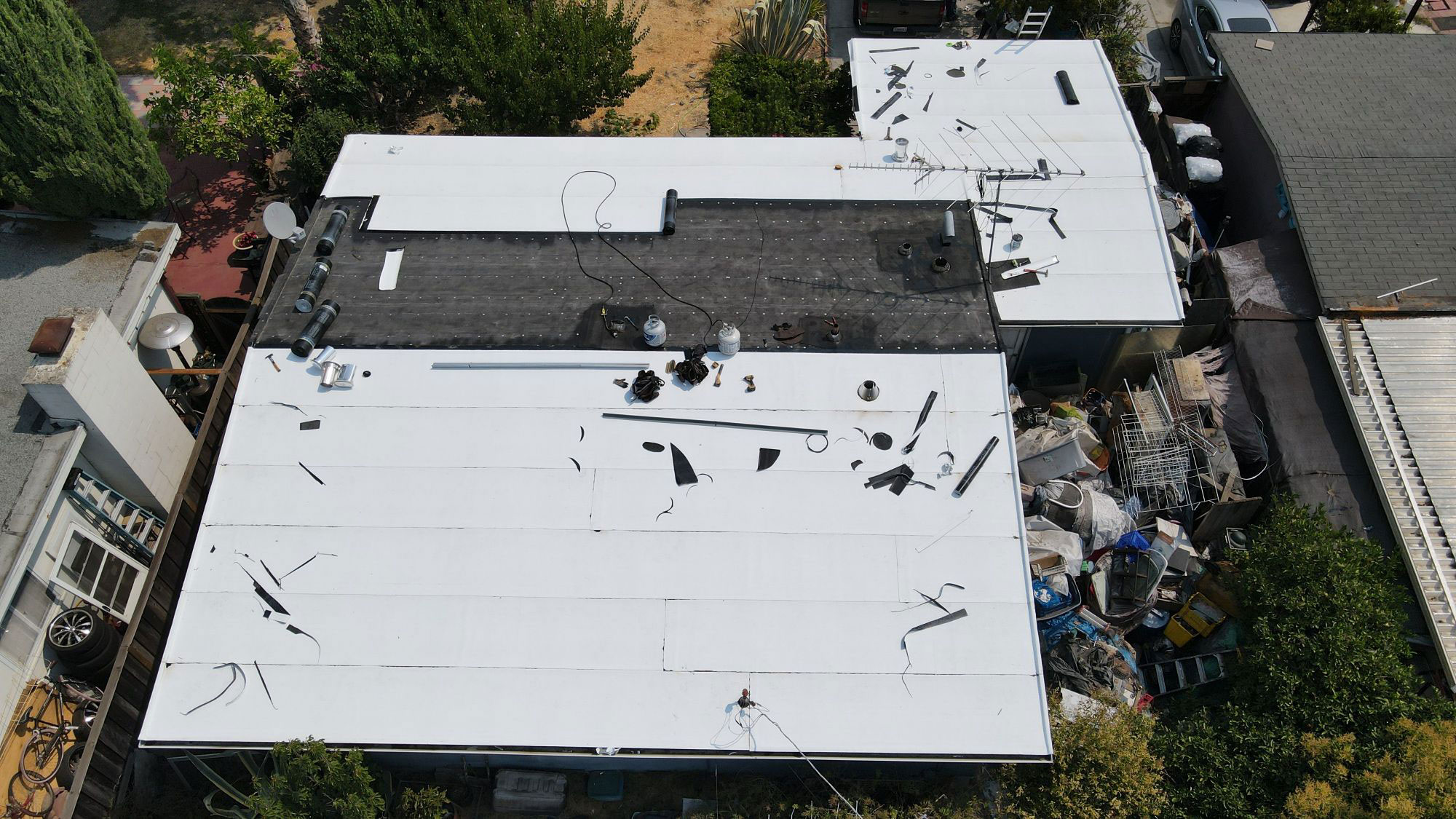 The image shows a building with a damaged roof, revealing a white surface underneath, possibly indicating recent construction or repair work.