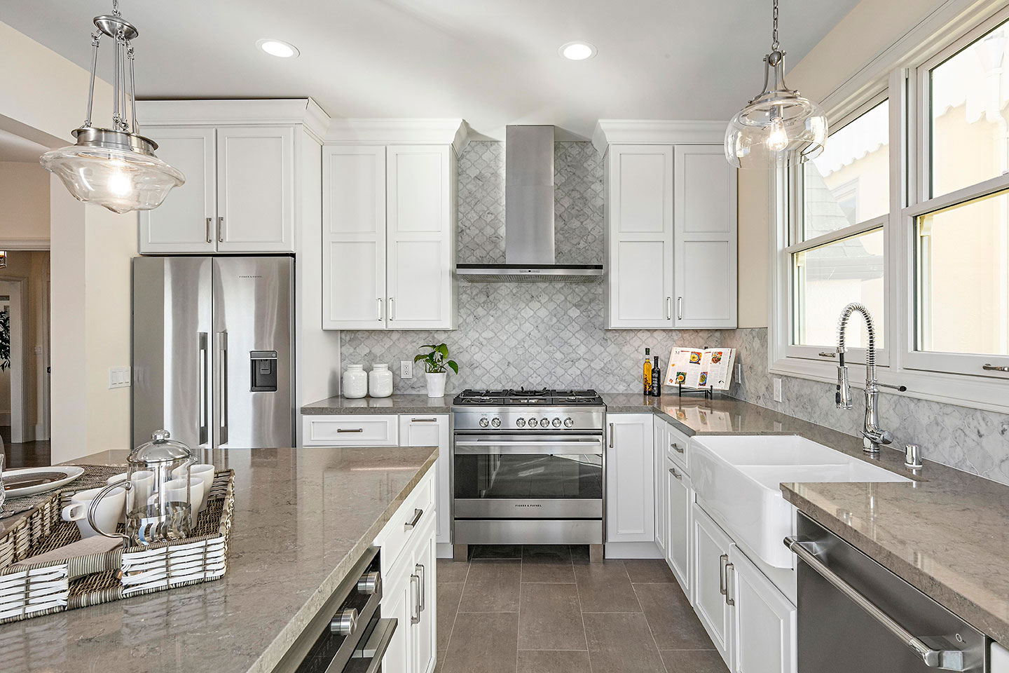The image shows a modern kitchen with white cabinets, stainless steel appliances, granite countertops, and a backsplash featuring gray tiles.