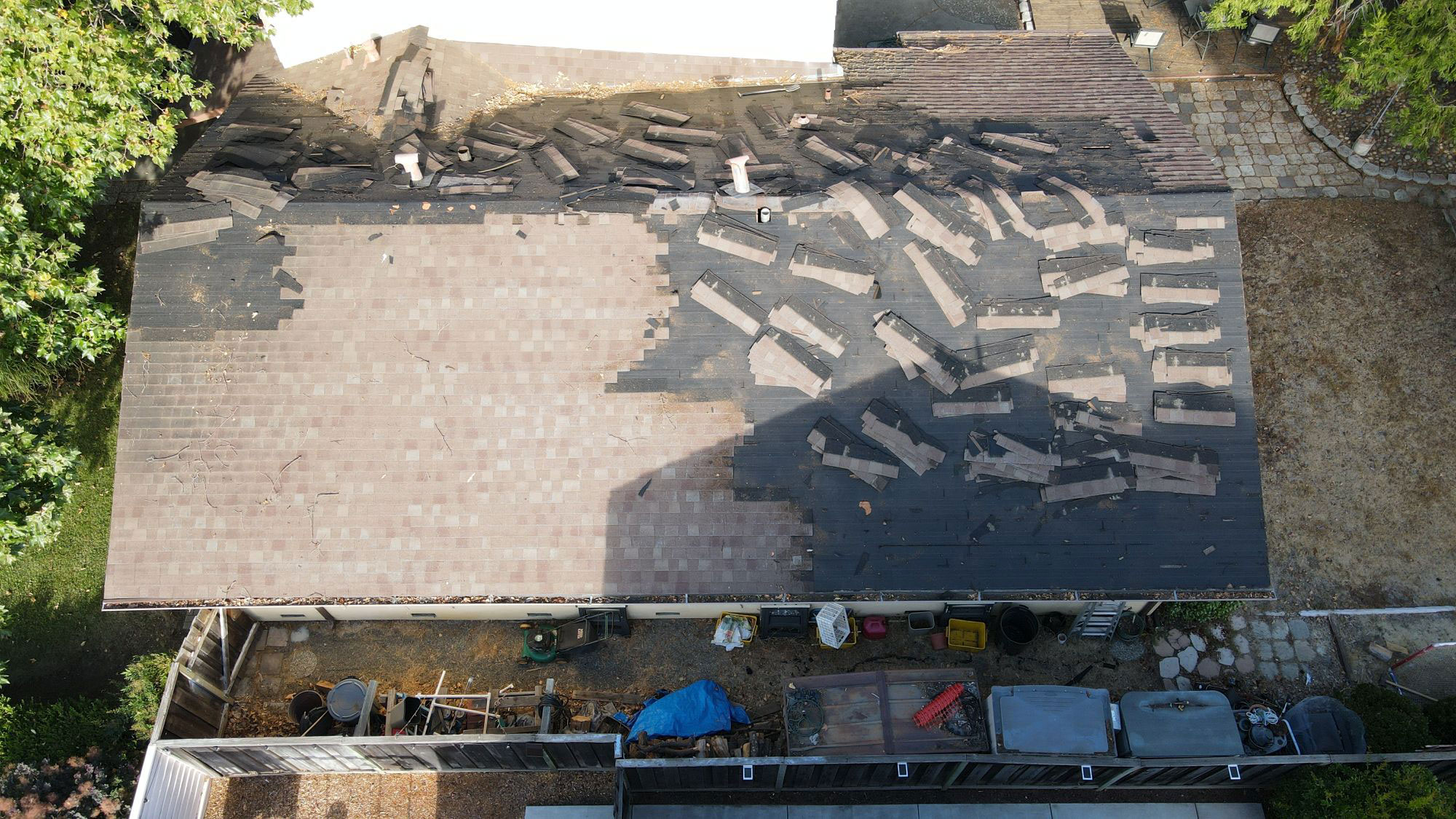 The image shows a building with a damaged roof, where several tiles are missing, exposing the underlying material.