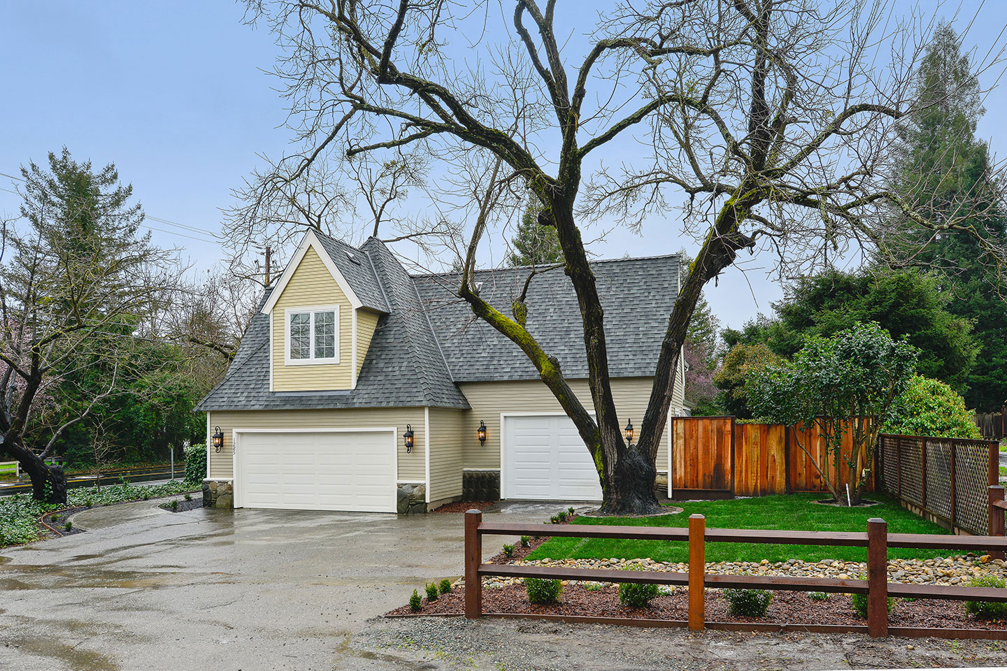 A two-story house with a garage door, set against a backdrop of trees and a clear sky.