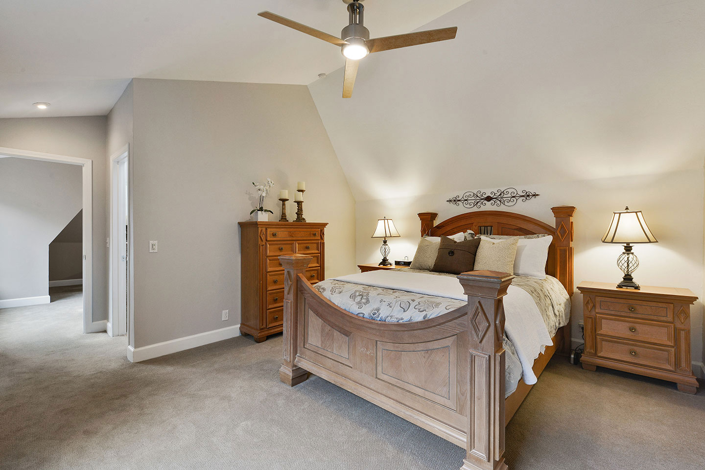 The image depicts an interior view of a bedroom with a large bed, nightstands, and a ceiling fan.