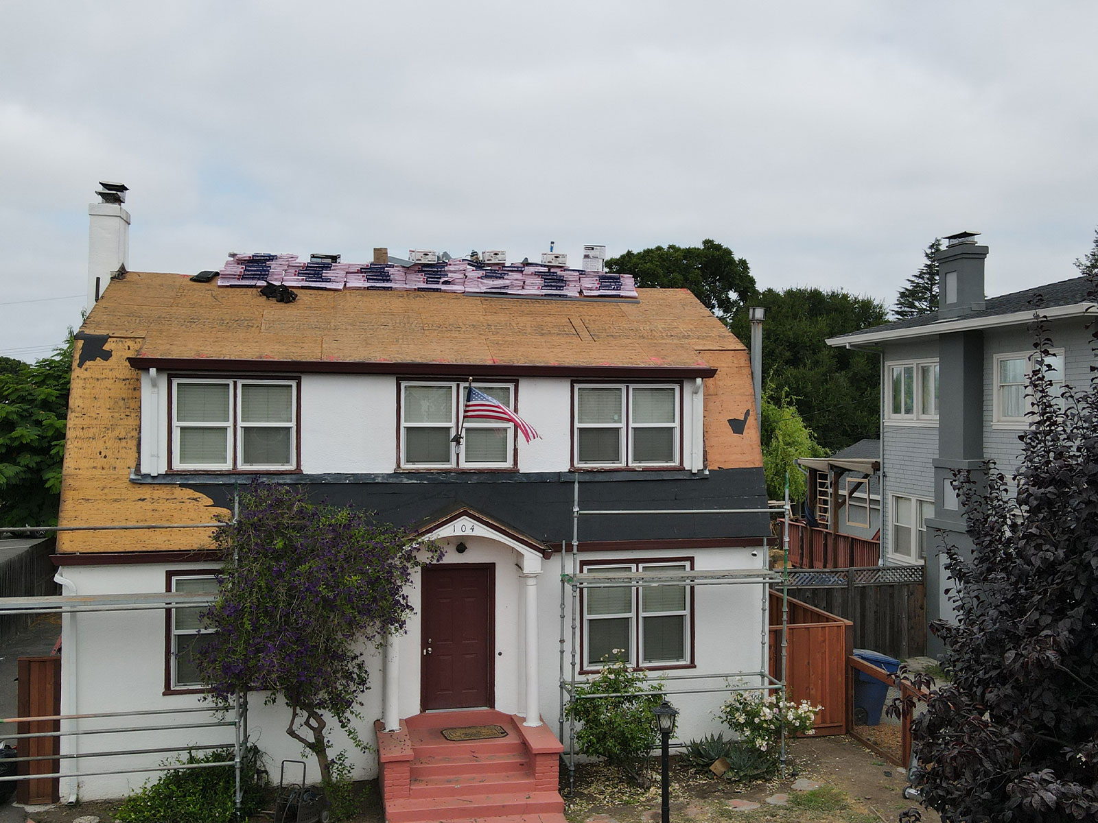 The image shows a two-story residential house with a flat roof under construction.