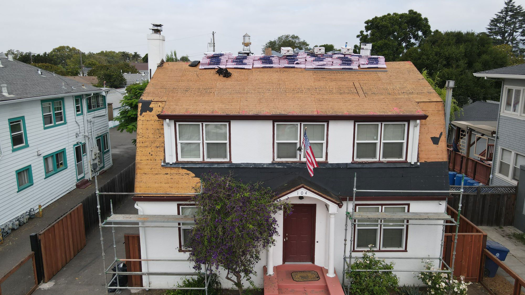 The image shows a two-story residential house with a solar panel installation on its roof.