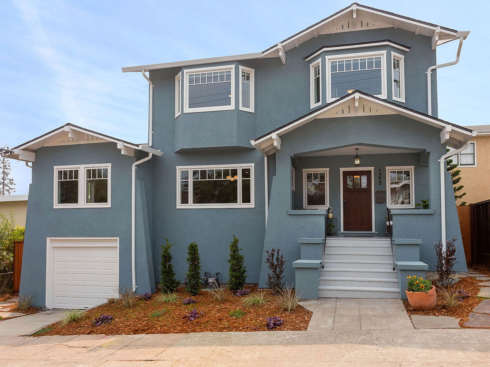 A two-story house with a large front porch, white trim, and a gray exterior.