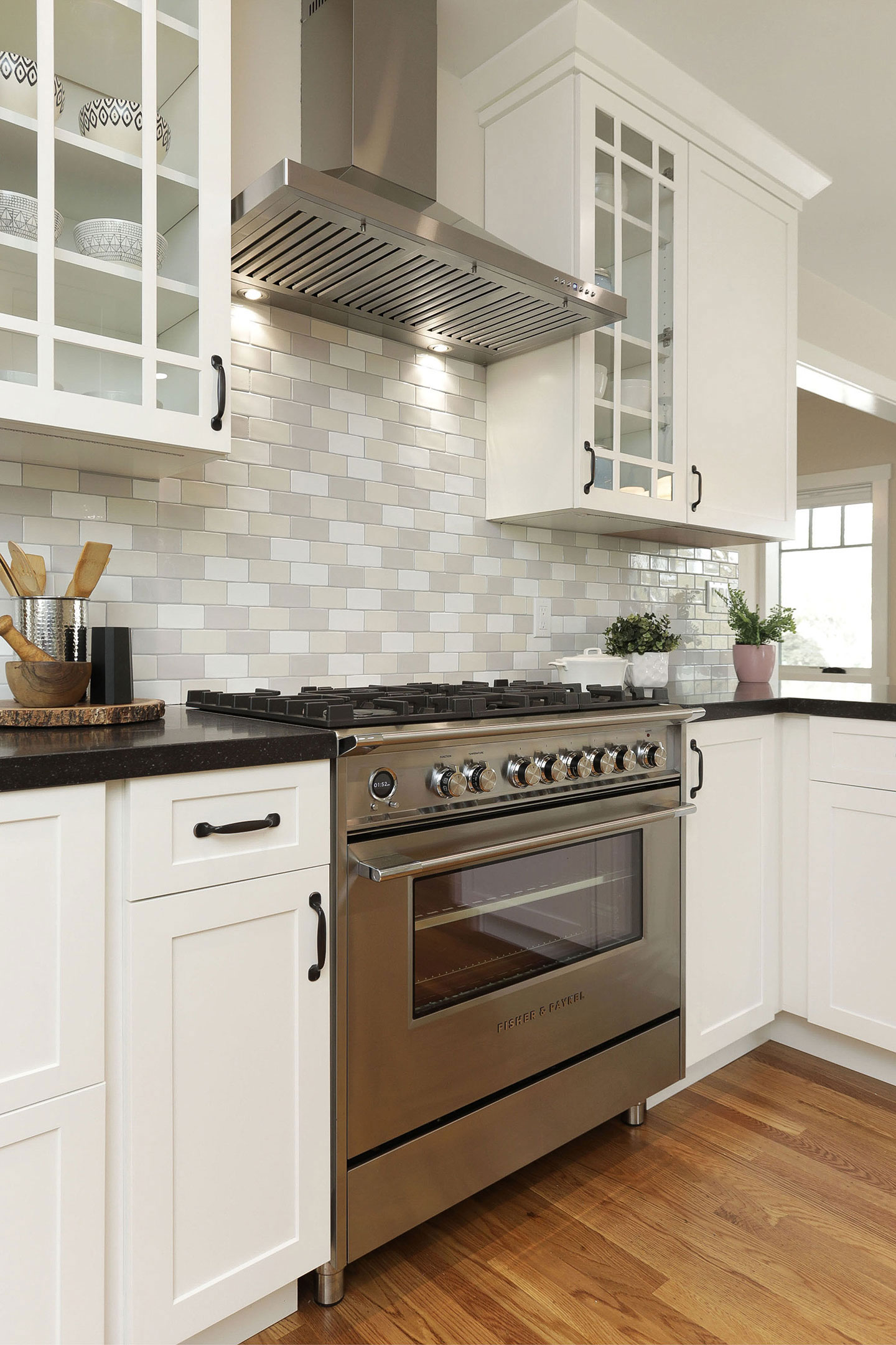 A modern kitchen with stainless steel appliances, white cabinets, and gray backsplash.