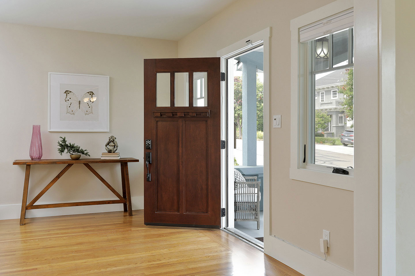 The image depicts a modern interior space with a dark wooden sliding door, which appears to be patio doors, leading outside. The room has a light-colored floor and walls, and there are no visible texts or distinguishing marks that provide additional context about the location or purpose of the space.
