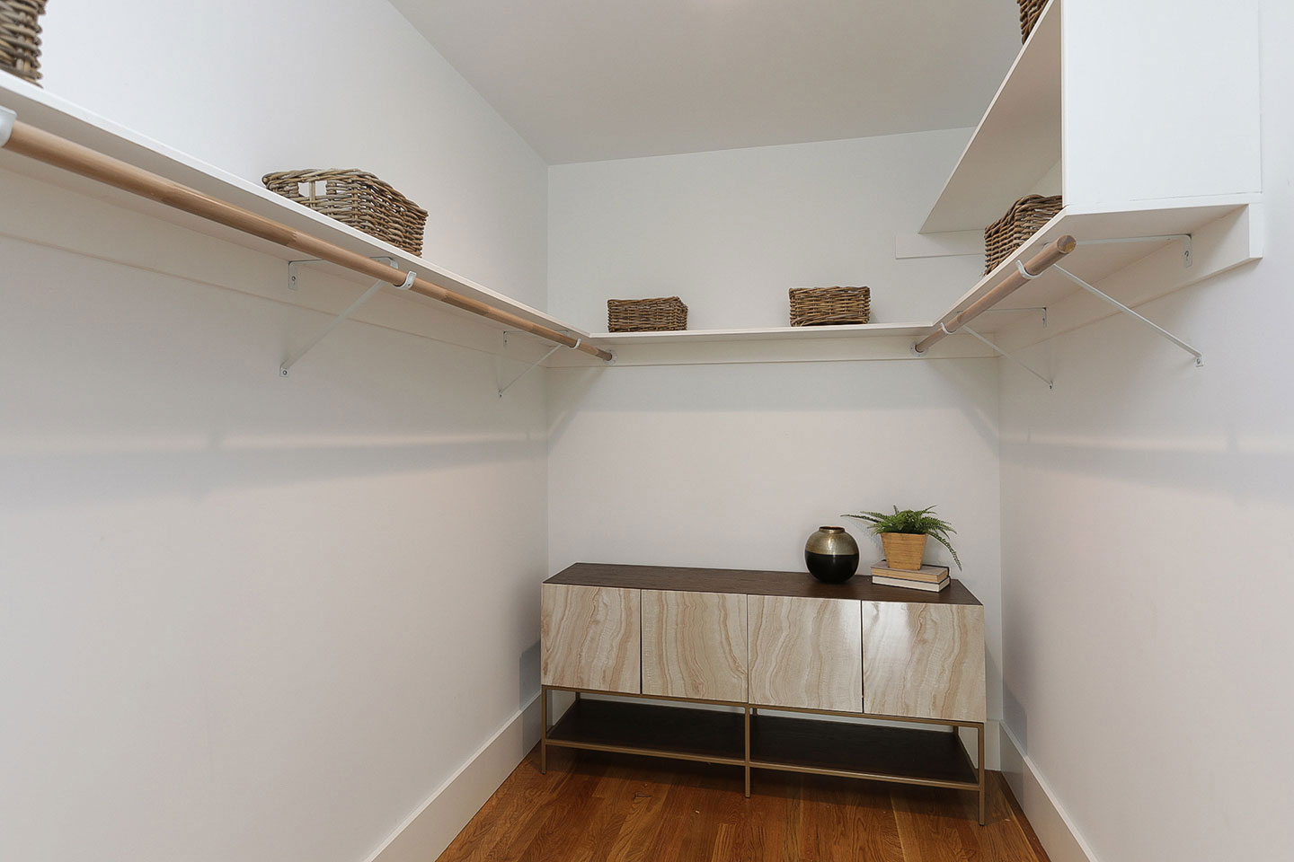 The image shows a neatly organized closet with shelves and hooks designed for storage, featuring a clean and modern aesthetic.