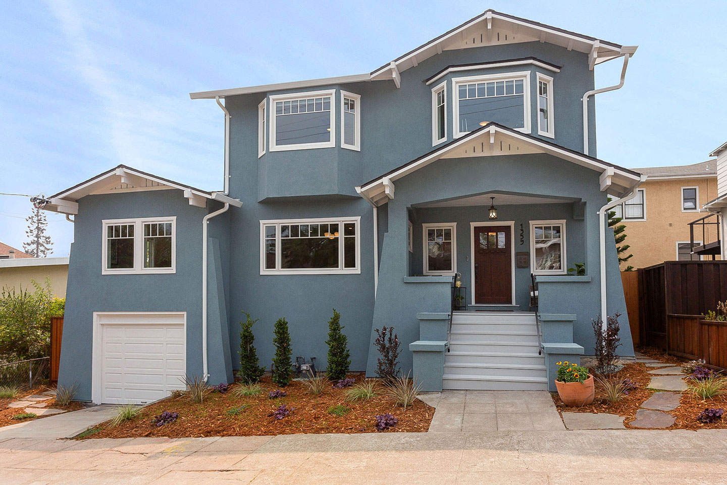 Large two-story residential house with light blue exterior, white trim, and attached garage.