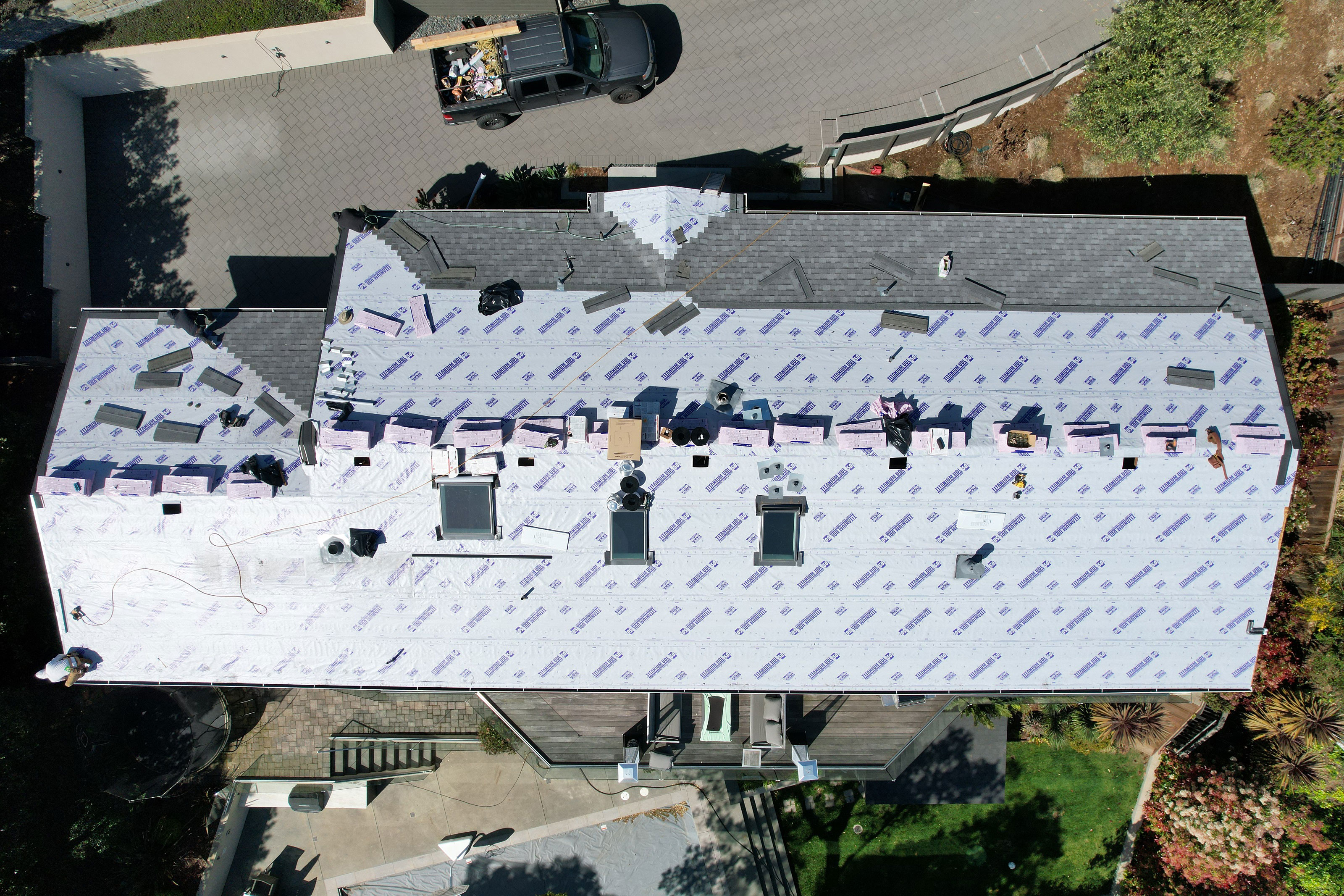 The image shows a residential building undergoing construction or renovation, with visible roofing materials and partially completed structures.