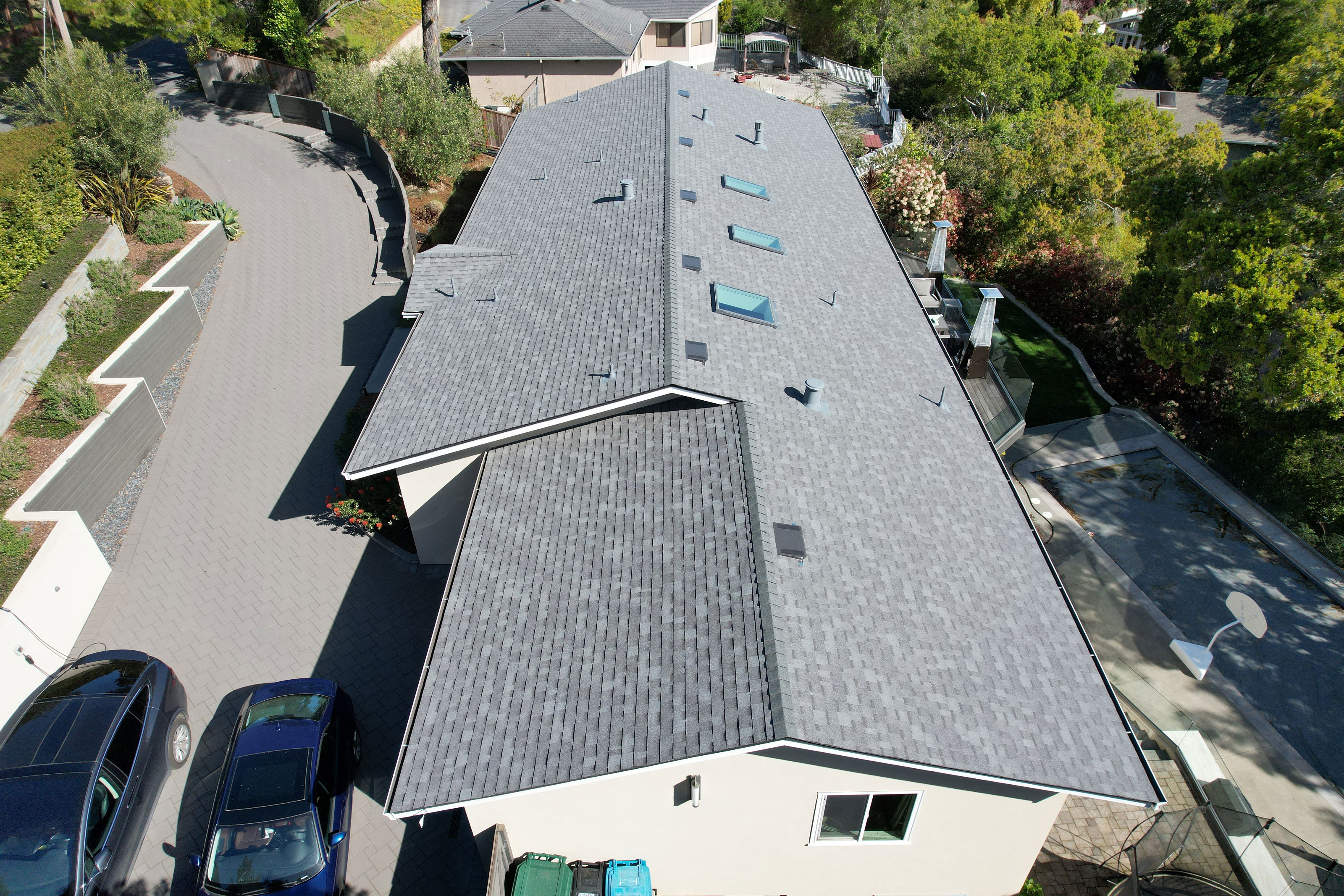 The image shows a single-story residential building with a pitched roof featuring multiple skylights and a large garage door at the front.