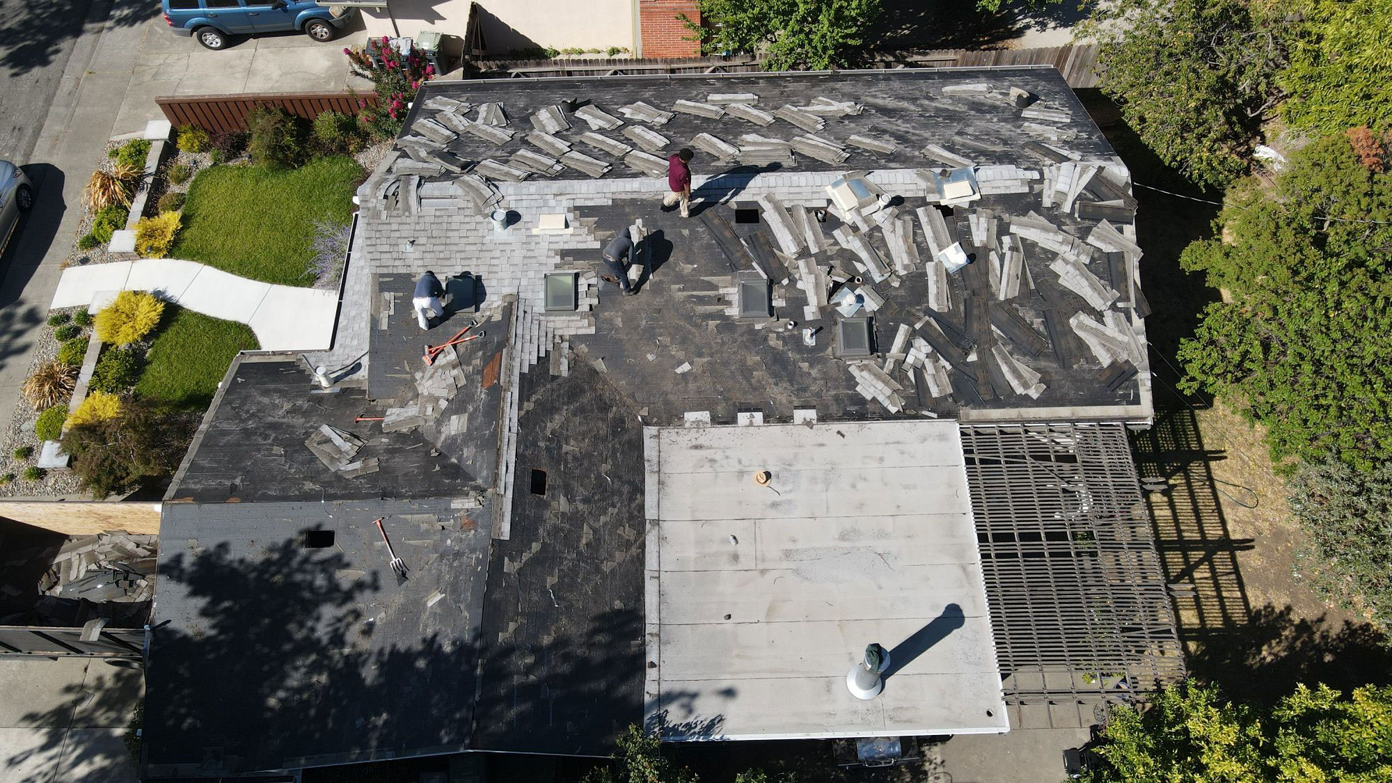 The image shows a building with a damaged roof, where some of the shingles are missing and exposed to the elements, revealing the underlying structure.