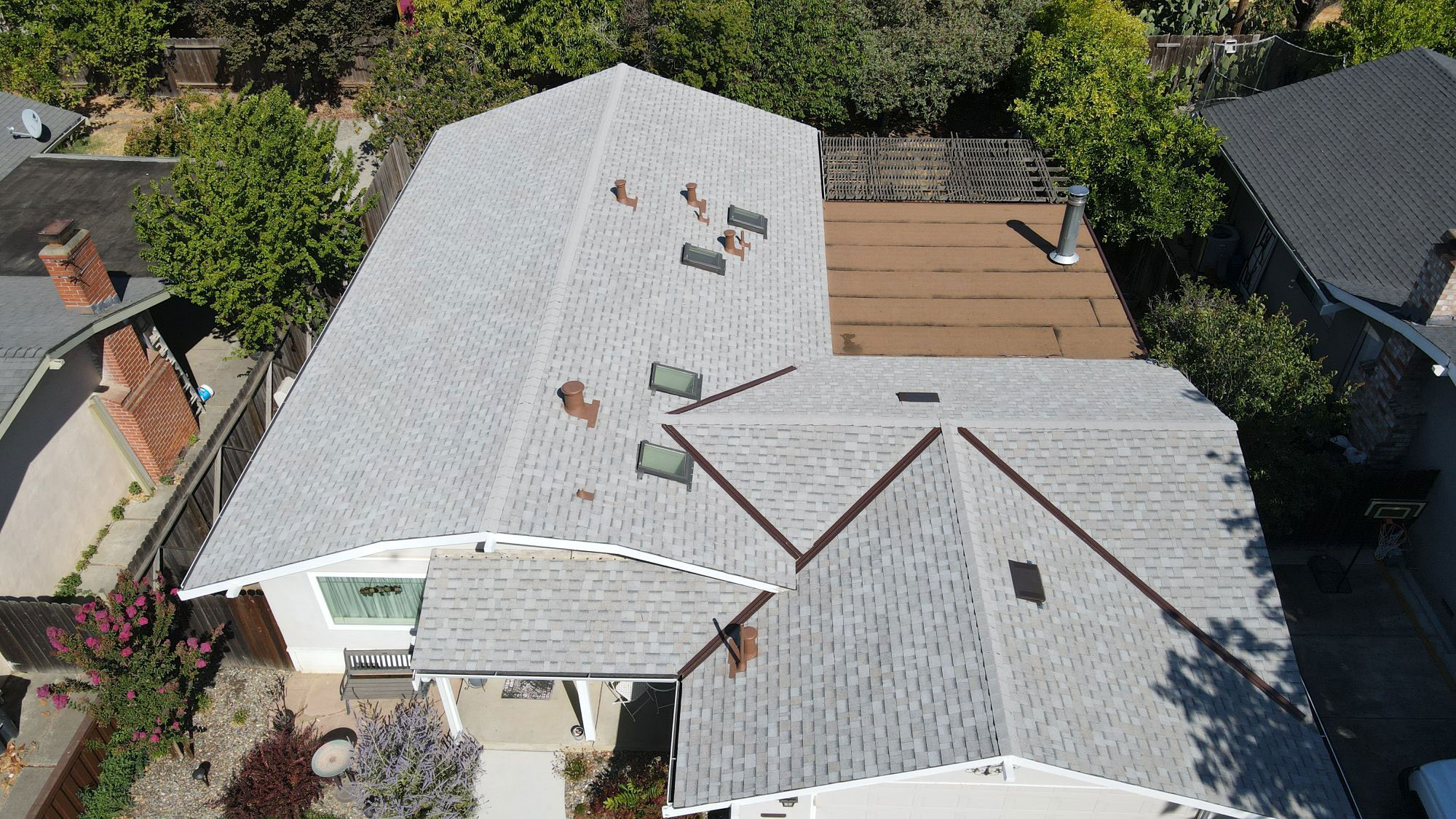 The image shows a house with a gray roof featuring multiple skylights and a flat design.