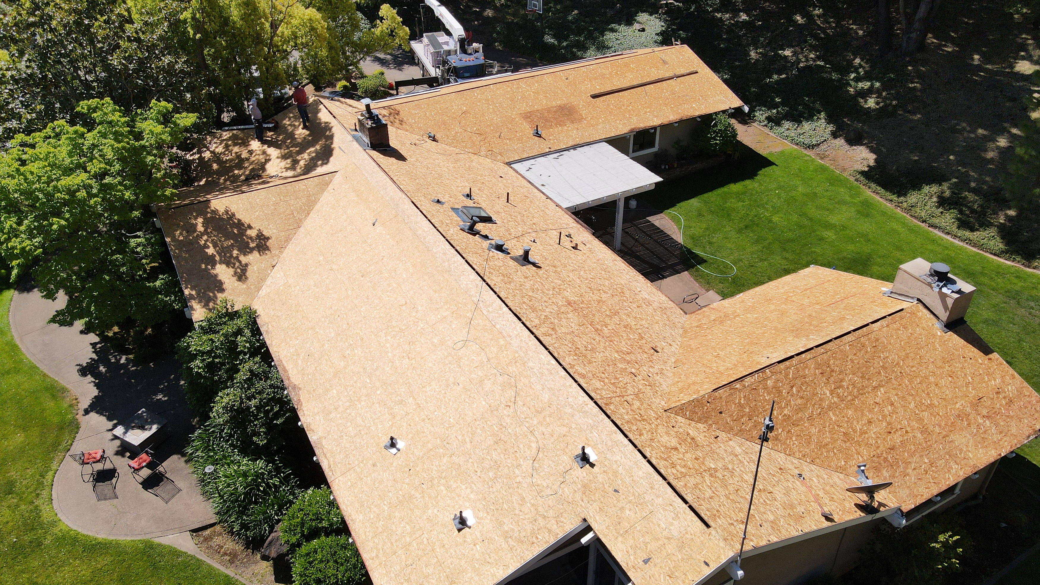 The image shows a house under construction with a visible roofing material applied.