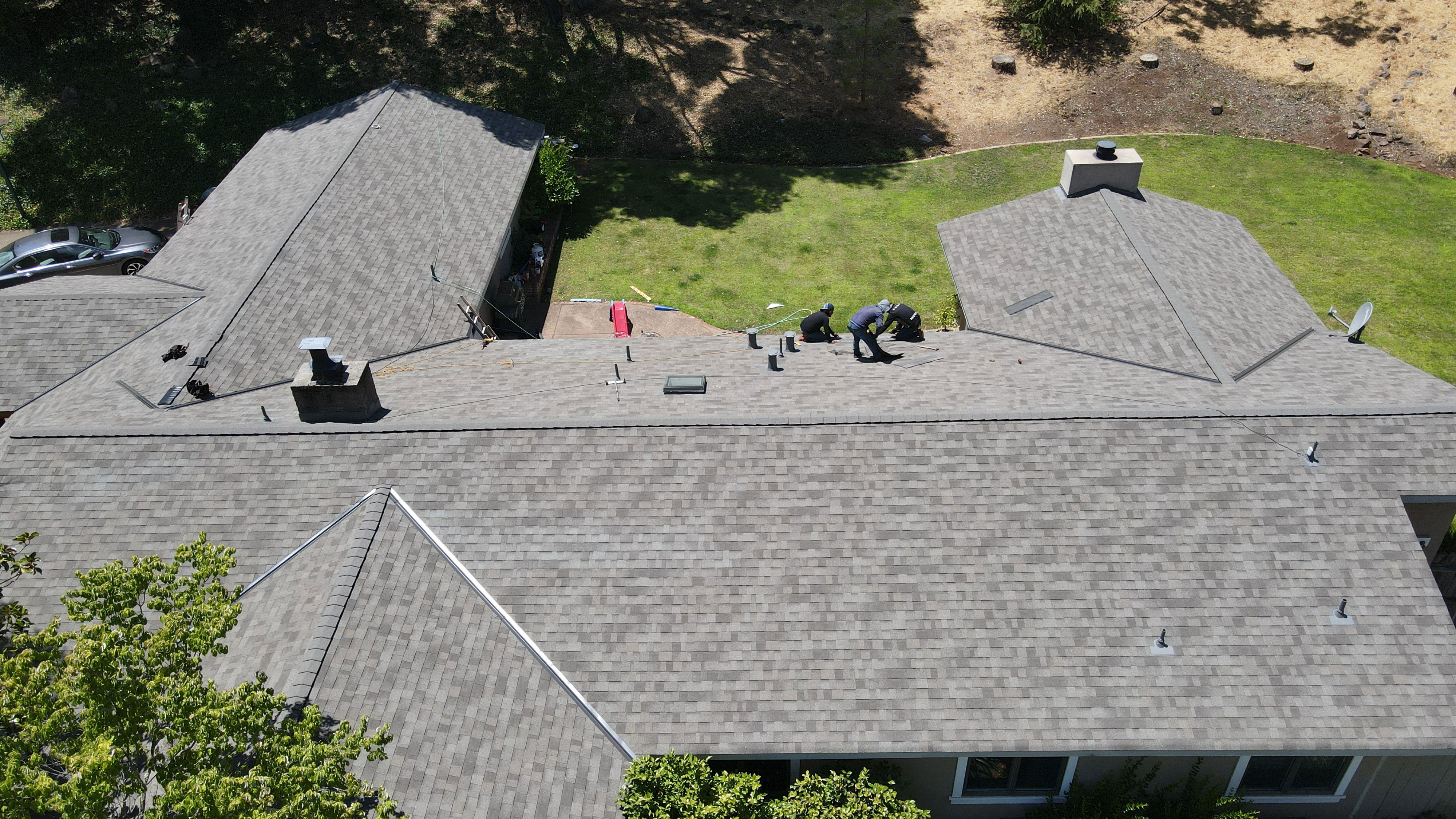 A roofing project underway on a residential house with shingles partially removed.