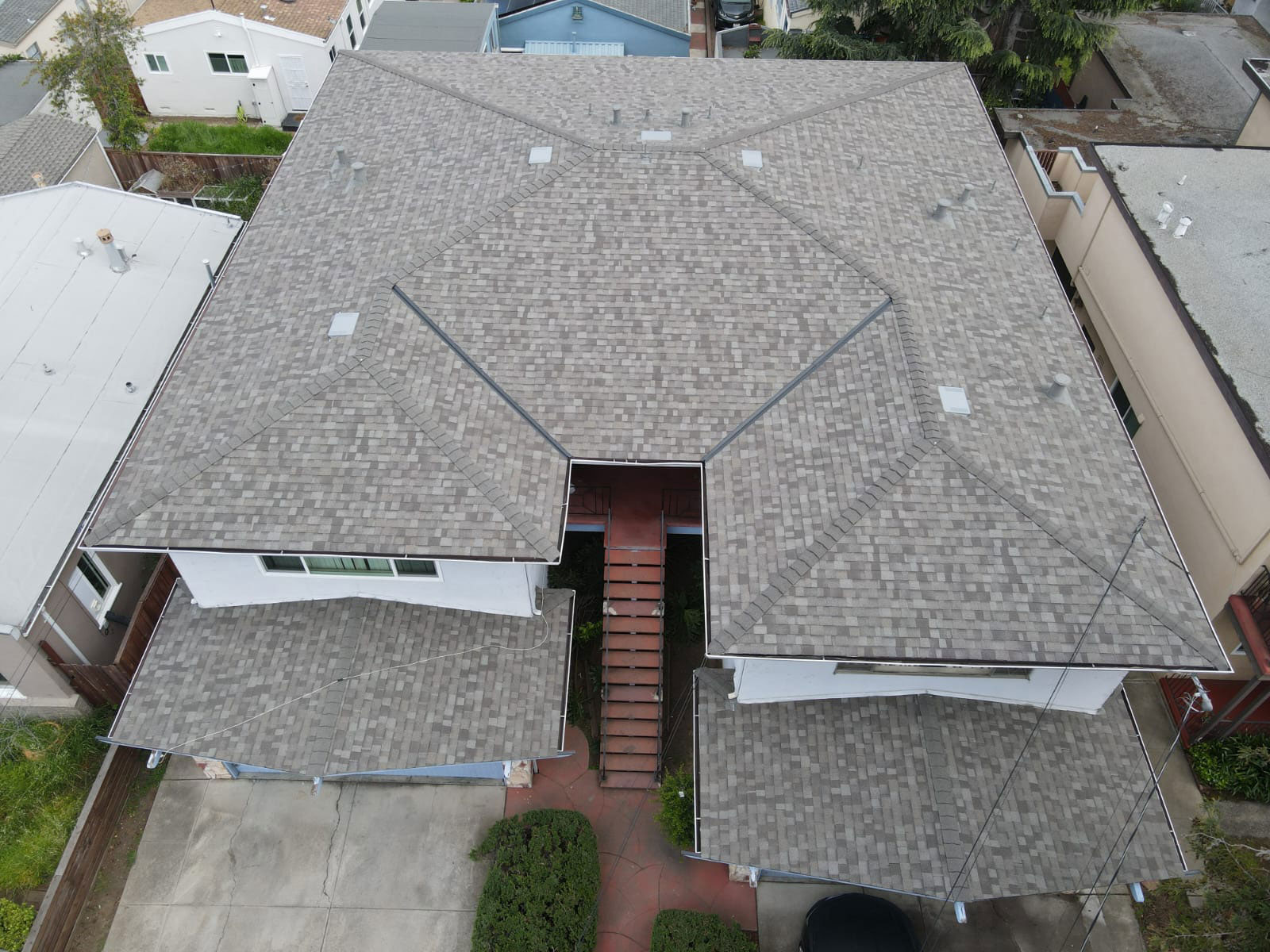The image shows a two-story residential house with a flat roof, visible from above, featuring a garage and a driveway.