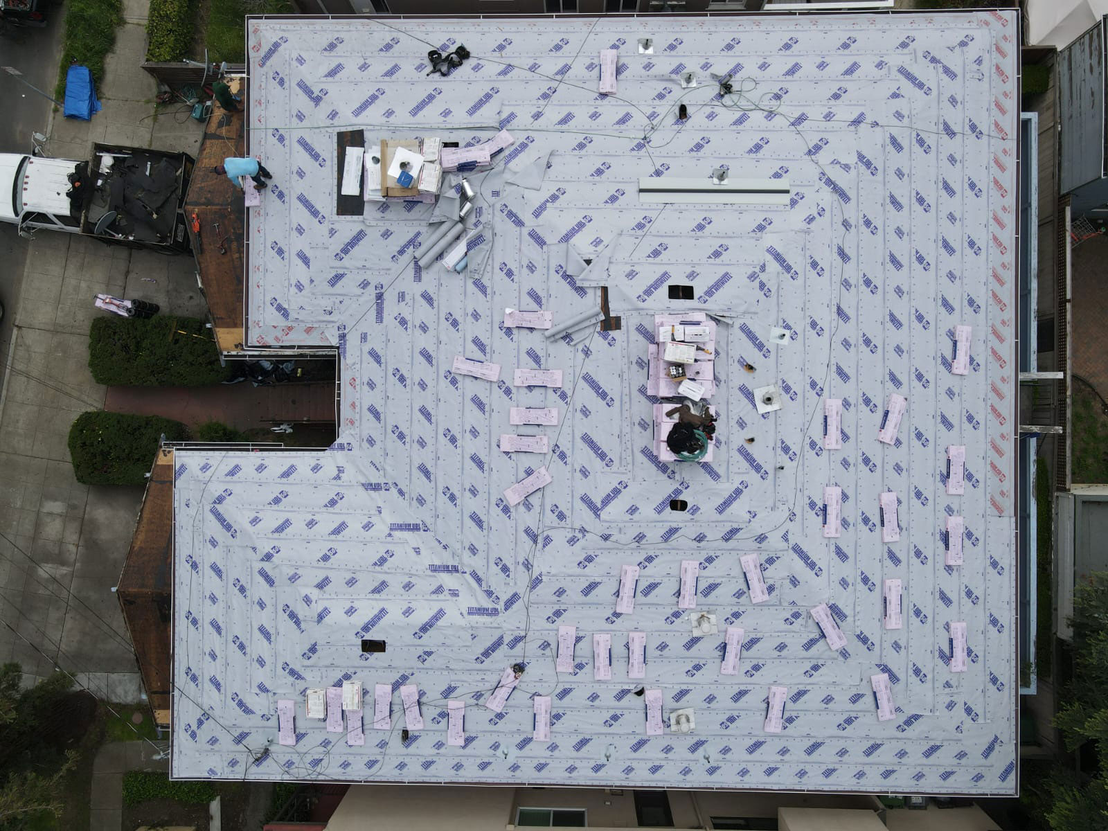 The image shows a flat roof under construction with visible building materials and construction equipment on top.
