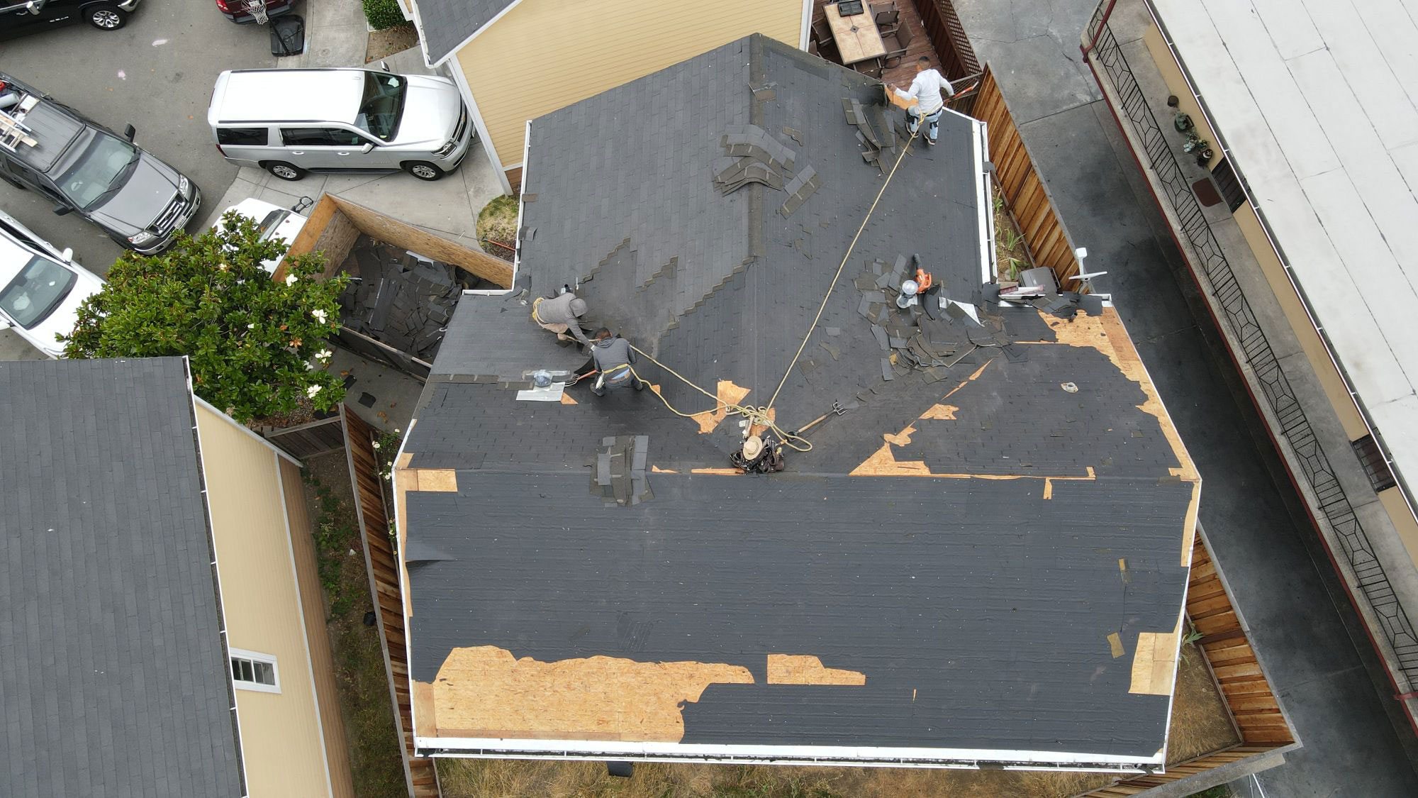 The image shows a residential building with a damaged roof under repair, indicating ongoing construction work.