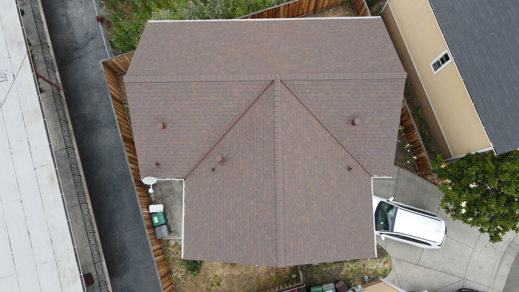 The image shows a house with a brown roof and a garage, taken from an elevated angle.