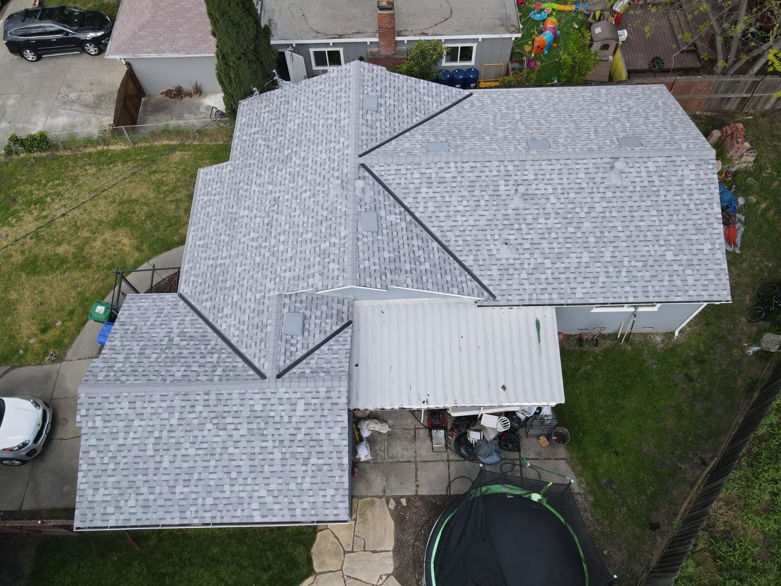 The image shows a house with a gray shingled roof under construction, featuring a prominent peak with a darker shade of gray, indicating a different material or color variation applied to this area.