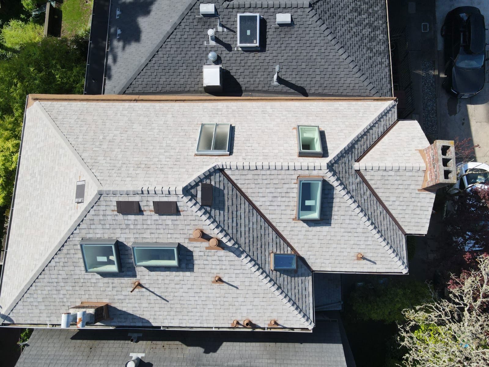 The image shows an aerial view of a residential building with a sloped roof, featuring multiple skylights and dormer windows.