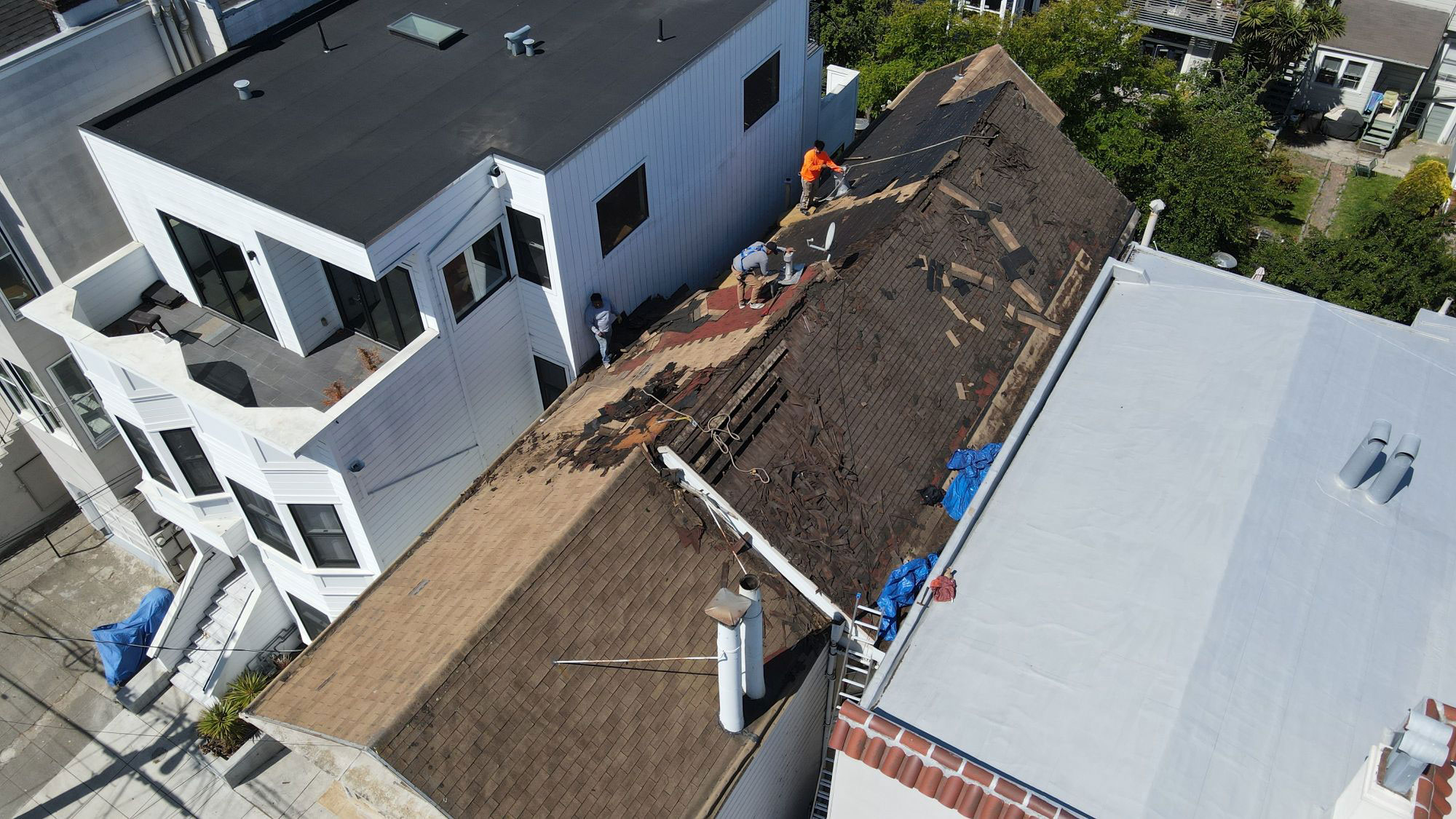A two-story house under construction with a visible roofing project underway.