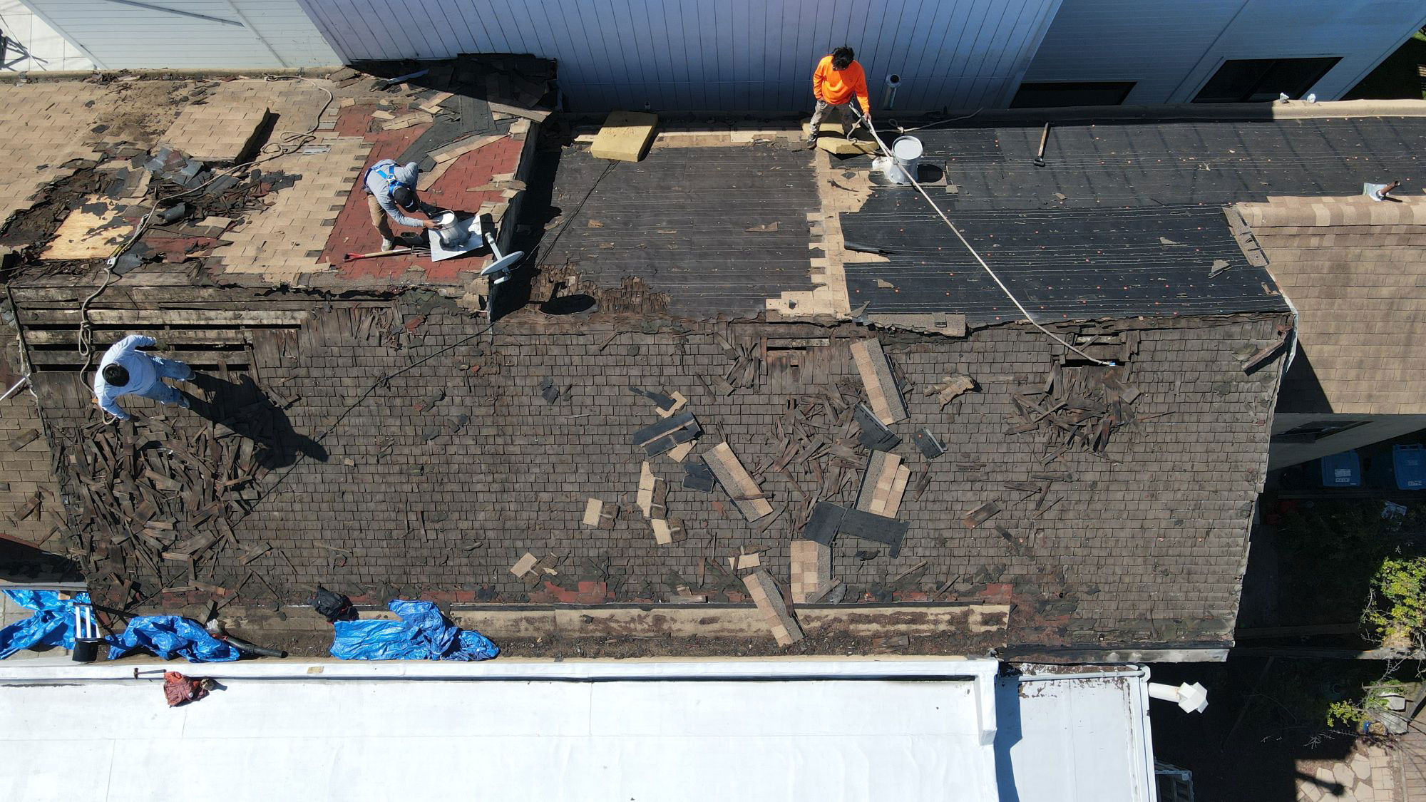 The image shows a building under construction with exposed roofing materials and workers engaged in the renovation process.