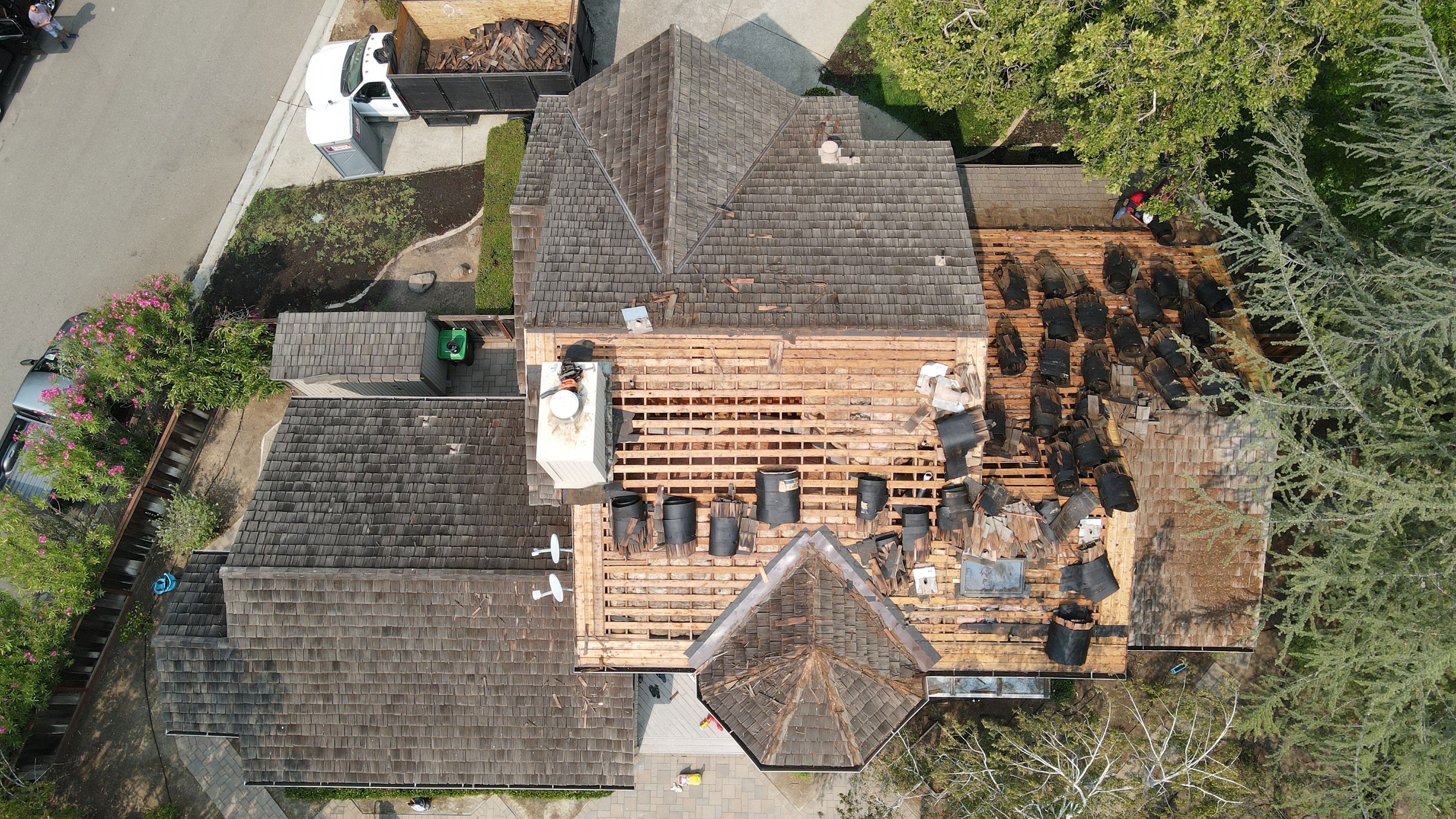 The image shows a house under construction with a visible roof and partially completed exterior walls.