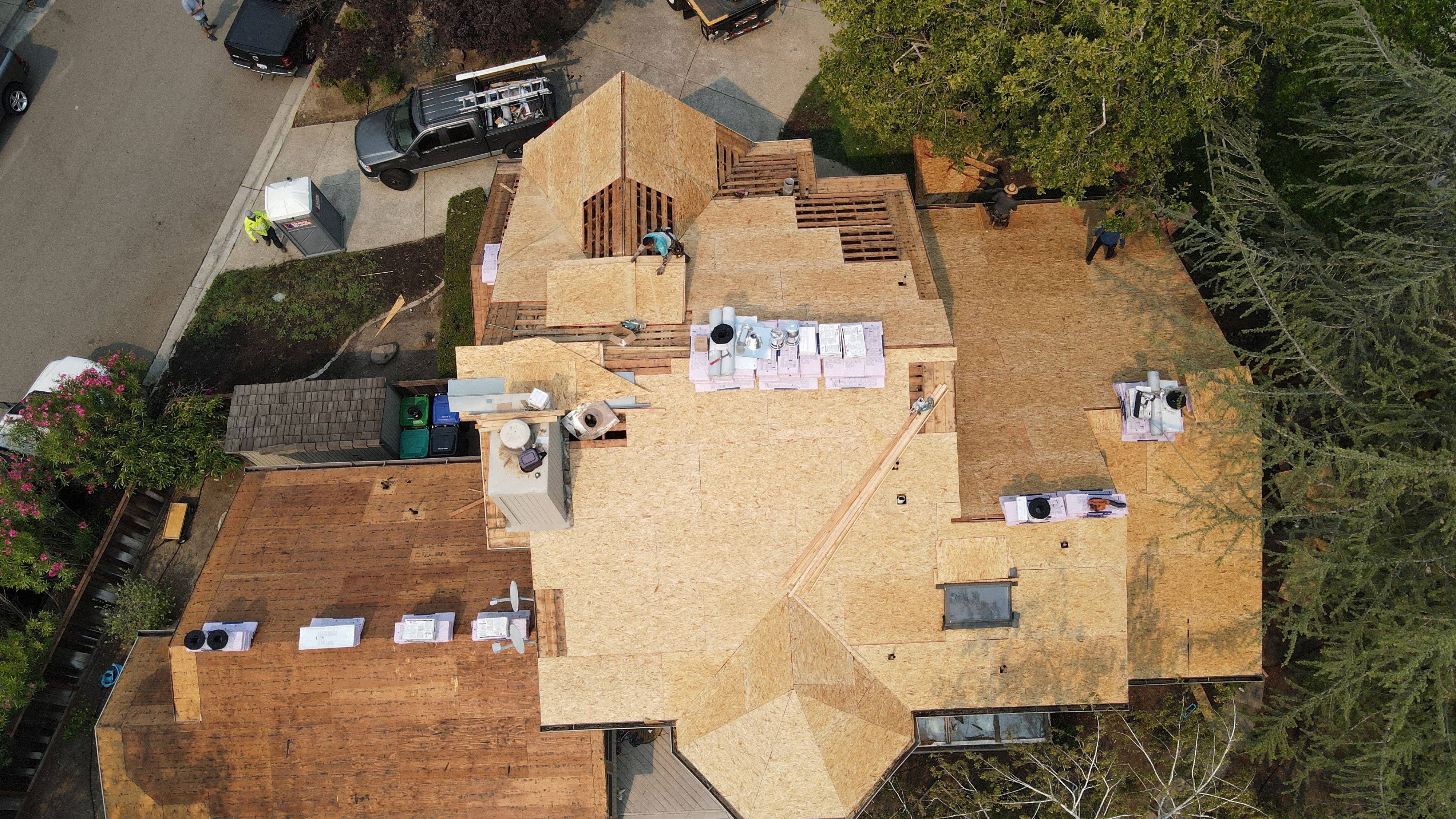 A large house under construction with visible wooden framing and roofing materials.