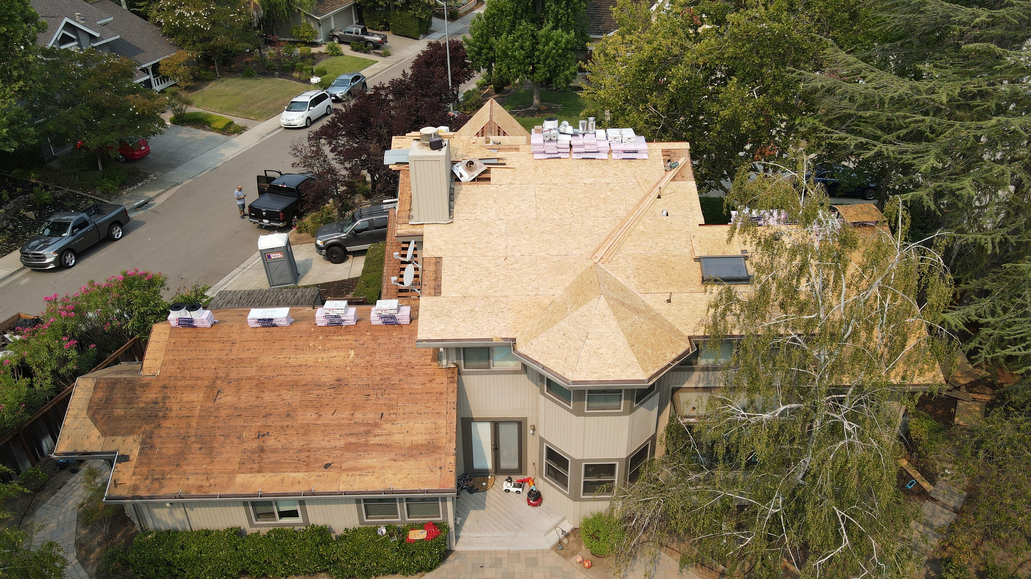 The image shows a residential property with a roof partially covered by a scaffolding structure, likely undergoing renovation work, featuring an open-air design with visible wooden planks on the upper level.