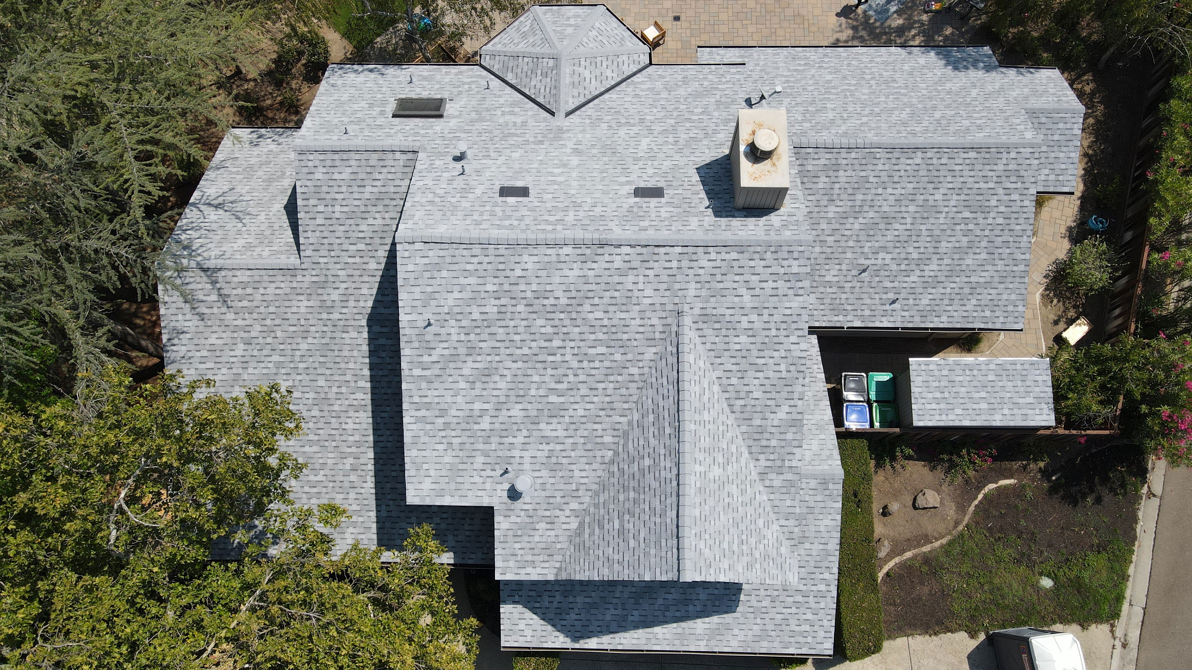 An overhead view of a house with a distinctive roof design resembling a face, featuring a prominent nose and eyes, set against a clear sky.