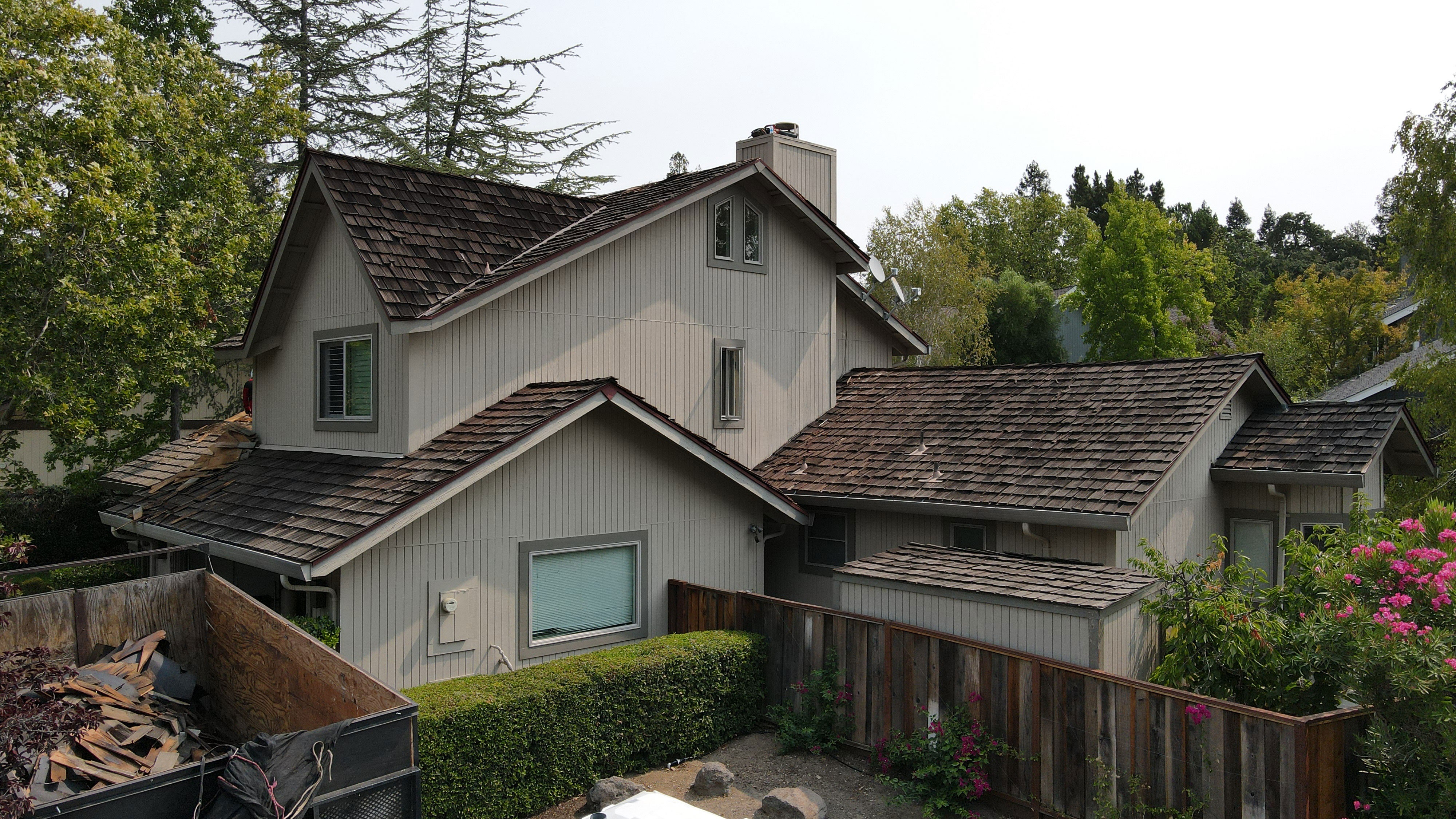 The image shows a two-story residential house with a shingled roof, a garage, and a well-maintained yard.