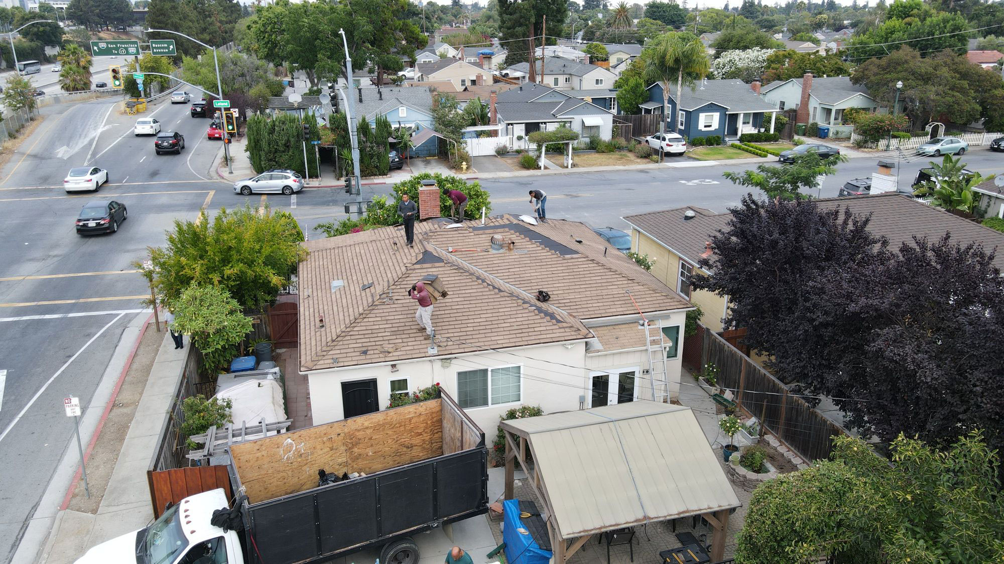 The image shows a residential street scene with houses, cars, and construction activity visible.