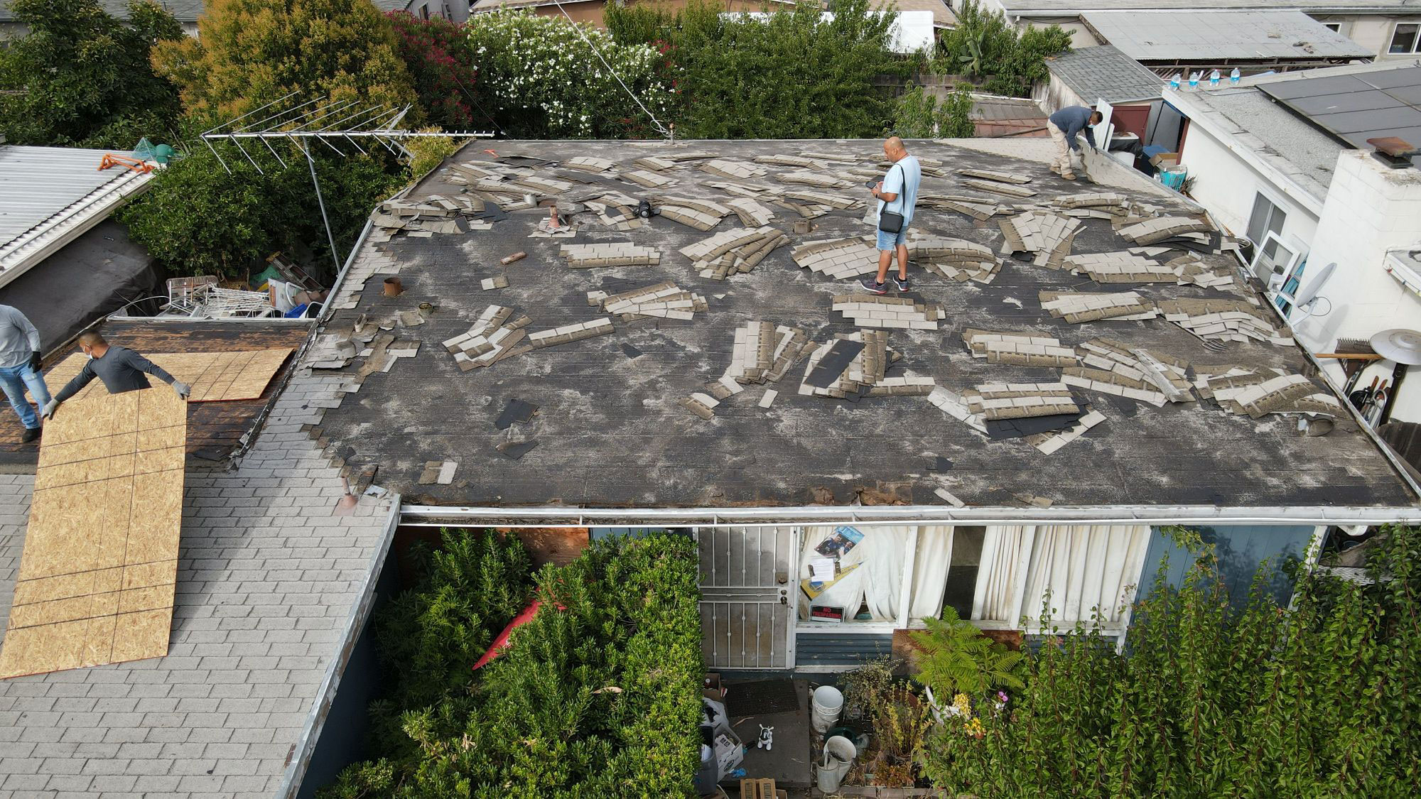 The image shows a roof under construction with various materials and tools scattered across its surface, indicating ongoing work.