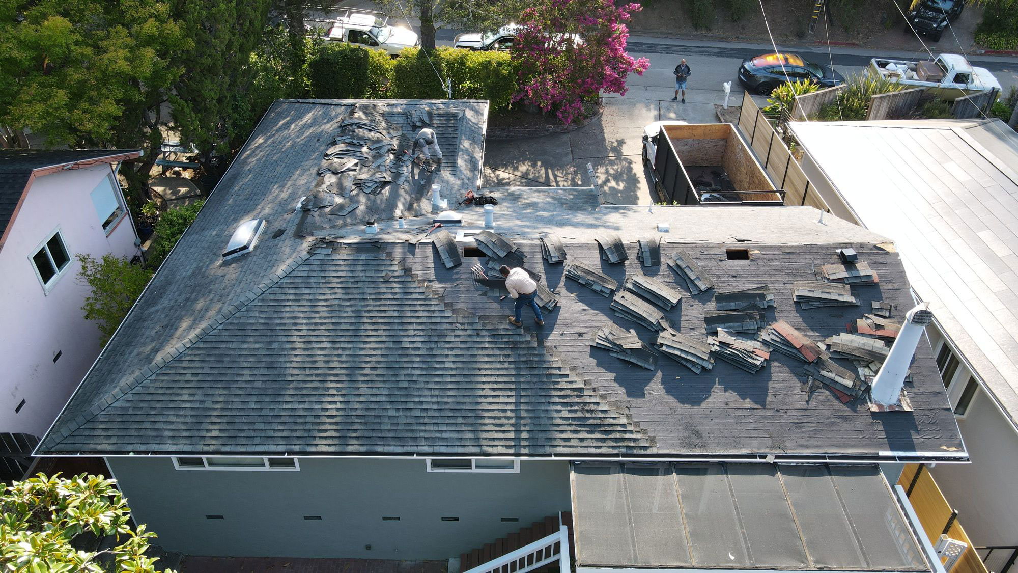 The image shows a building with a damaged roof, where several shingles are missing, revealing the underlying structure.