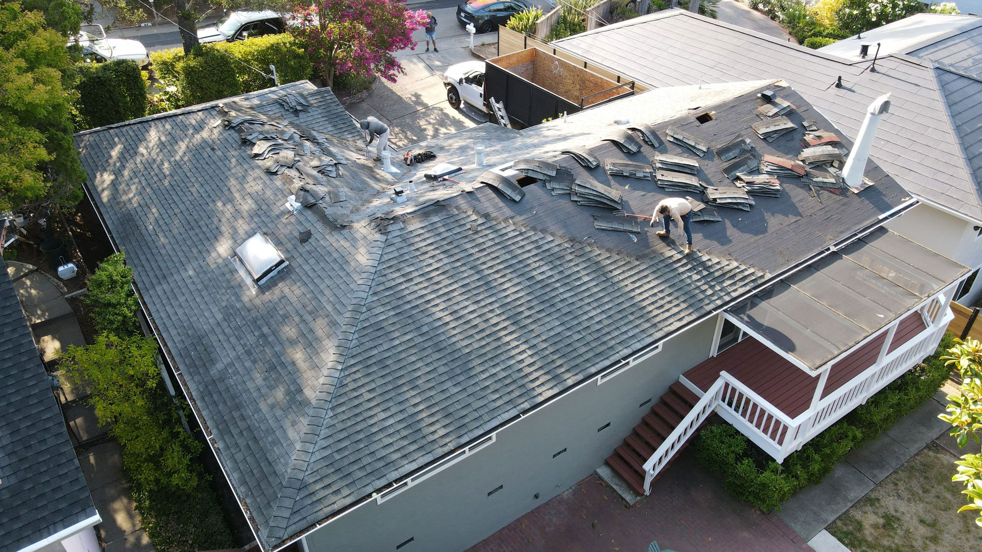 The image shows a house with a damaged roof, indicating recent severe weather conditions such as a storm or tornado.