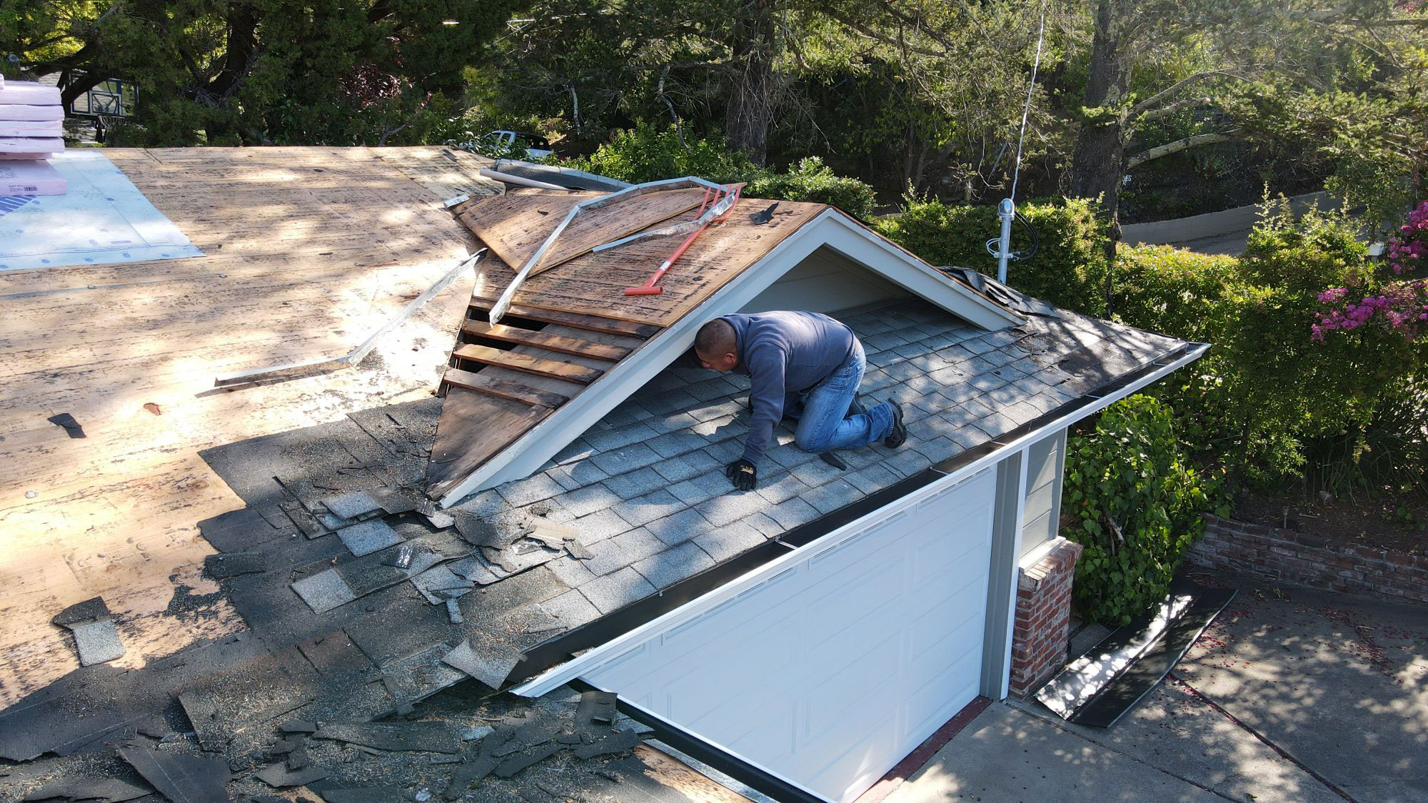 This is an image of a person working on the roof of a house during daylight hours.