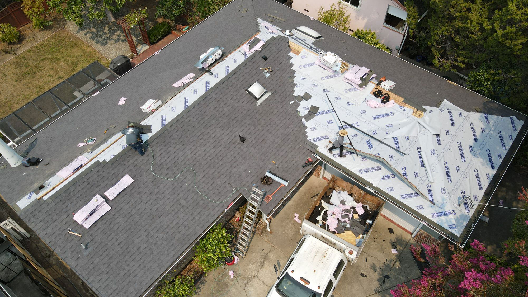 The image shows a roof under construction with visible insulation materials and some tools on the ground.