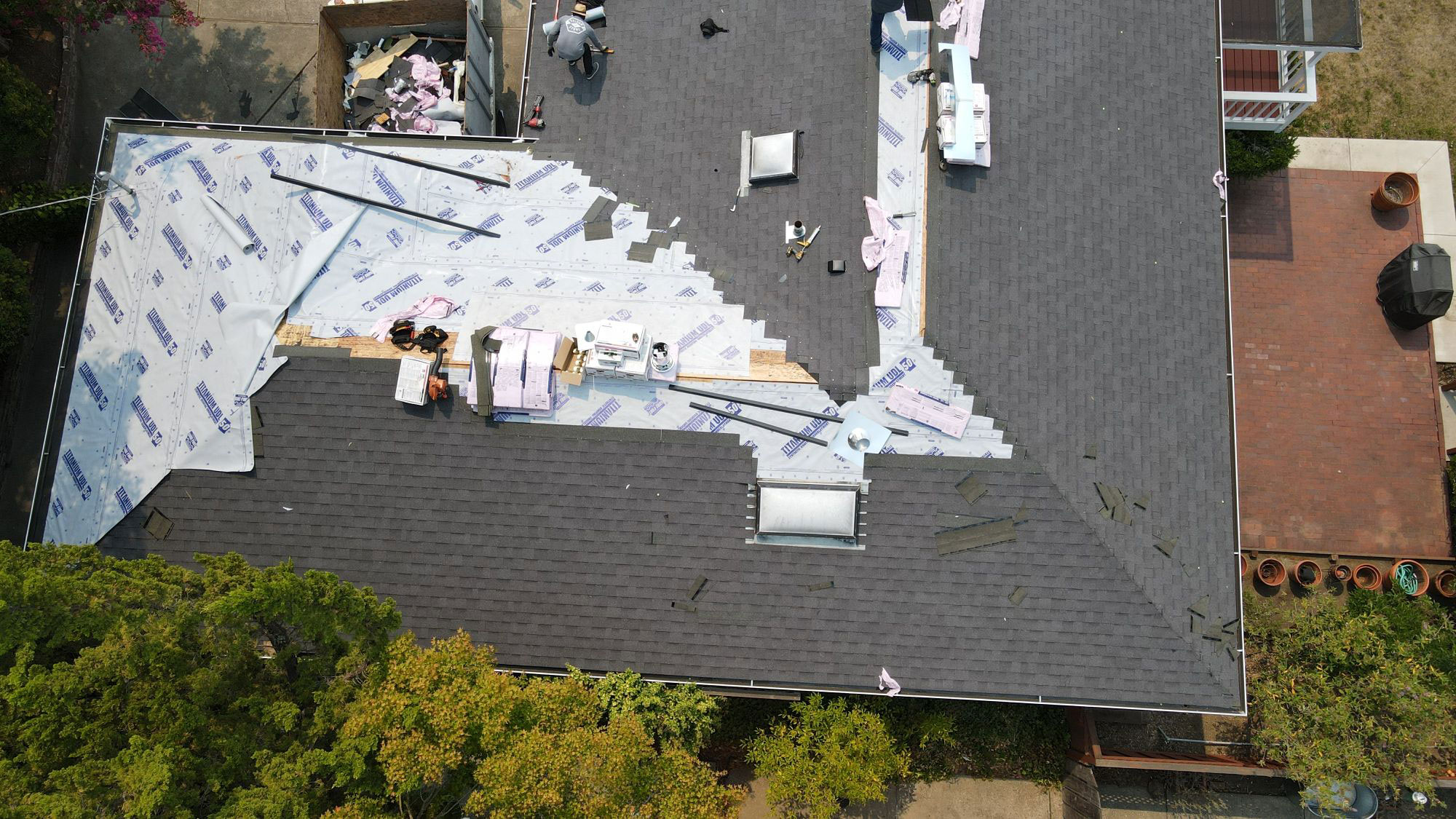 The image shows a roof under construction with visible insulation materials on the ground.