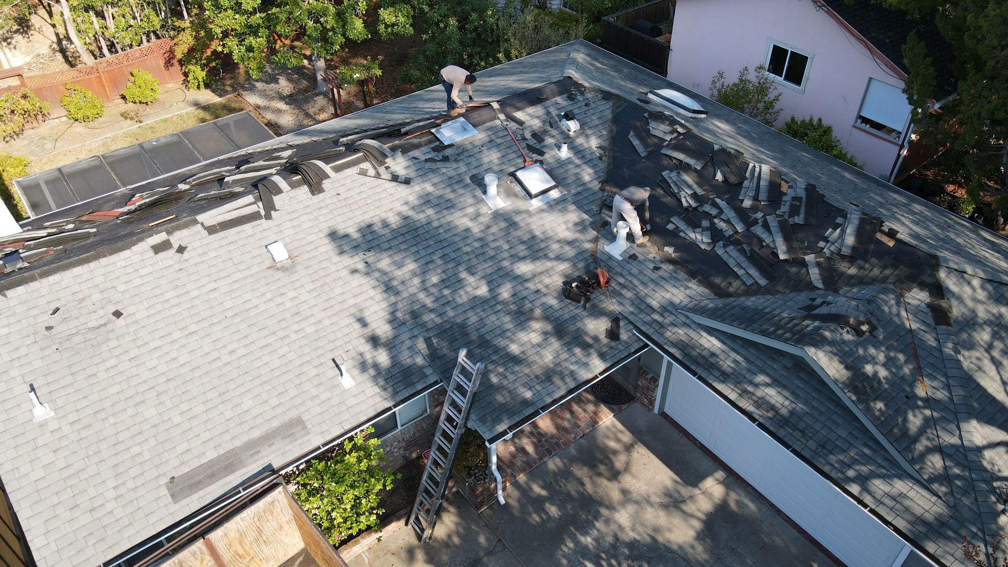The image shows a residential roof undergoing renovation with visible materials such as shingles and insulation exposed, indicating ongoing work.