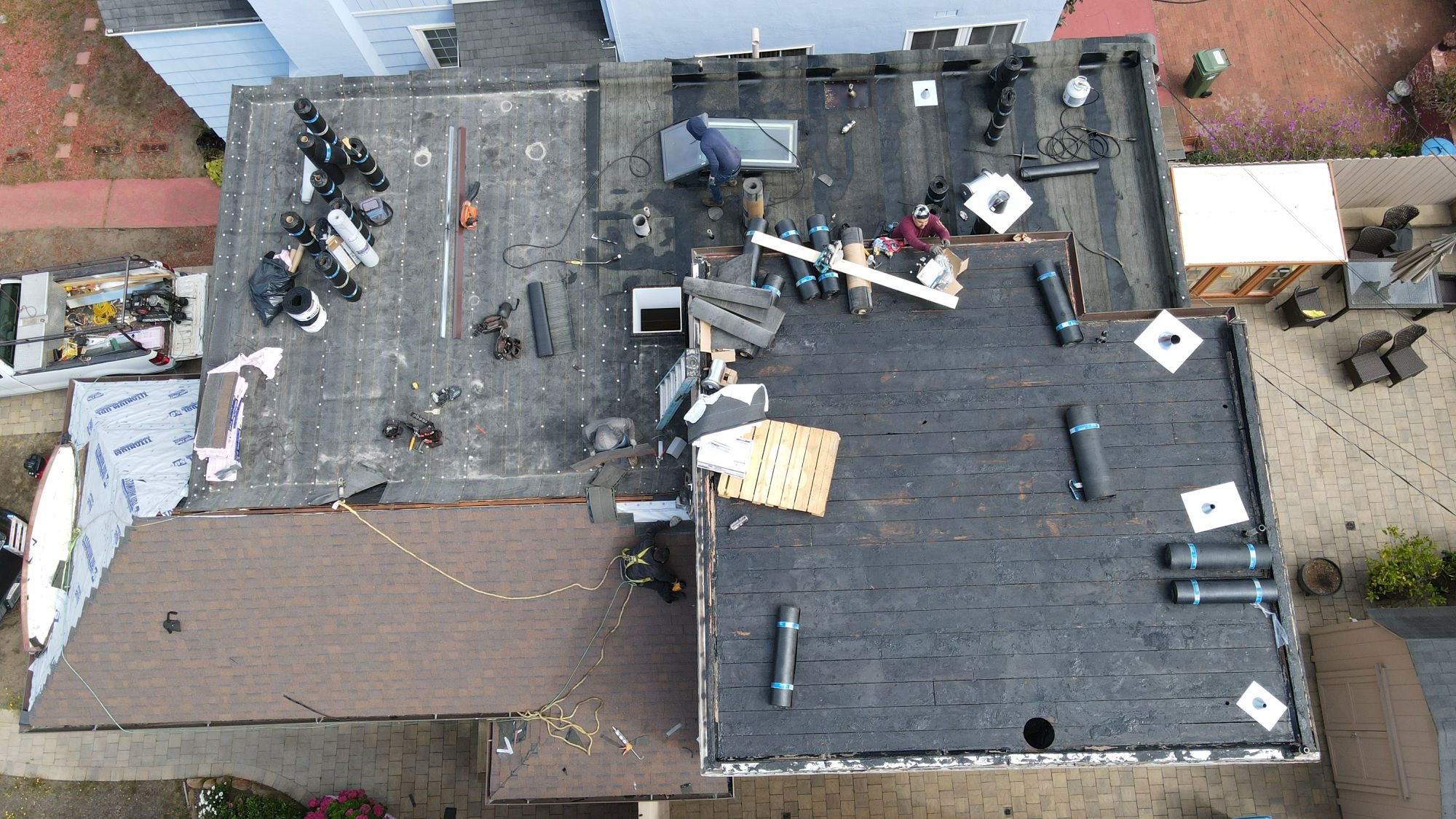 The image shows a building undergoing renovation with visible roof repairs and construction materials on the ground.