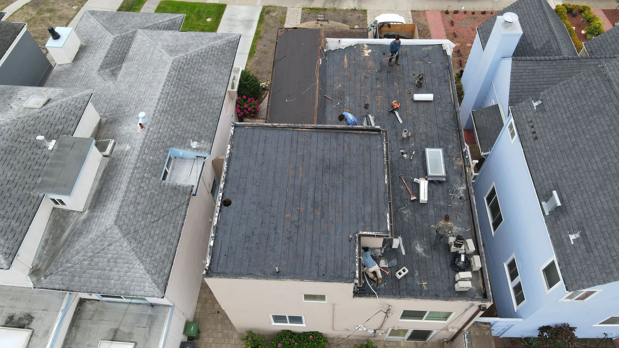 A residential house undergoing roof repair with visible tarps on the roof.