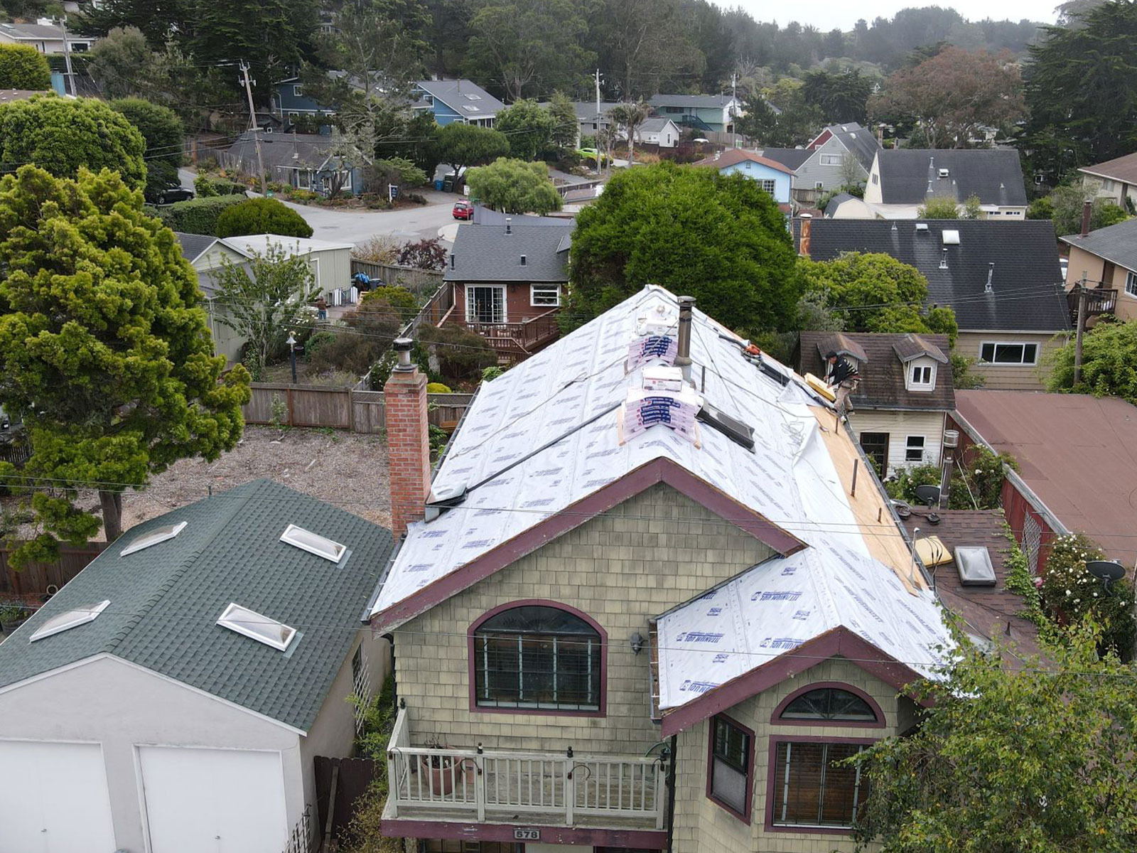 A house under construction with a visible roof covered by plastic sheeting.